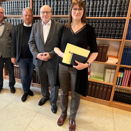 Vier Menschen vor Bücherwand