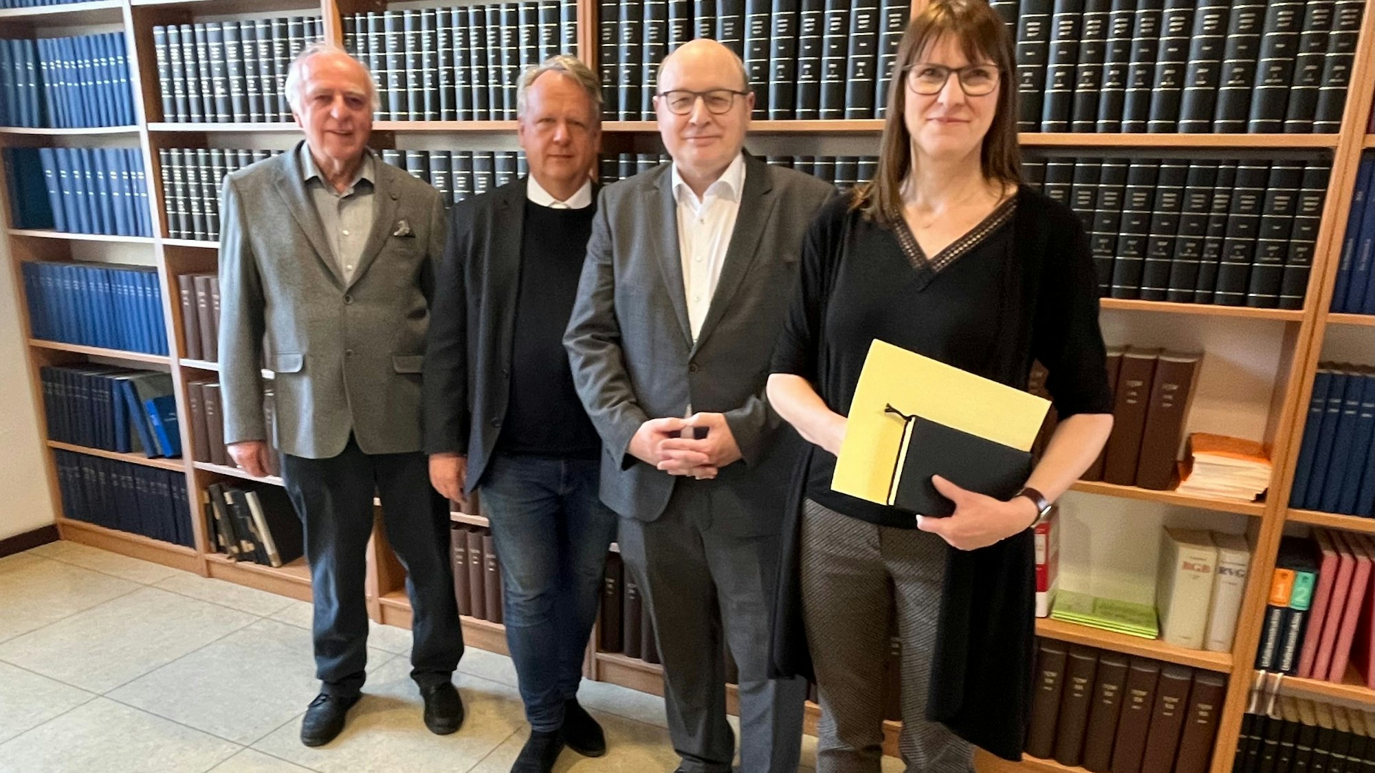 Vier Menschen vor Bücherwand