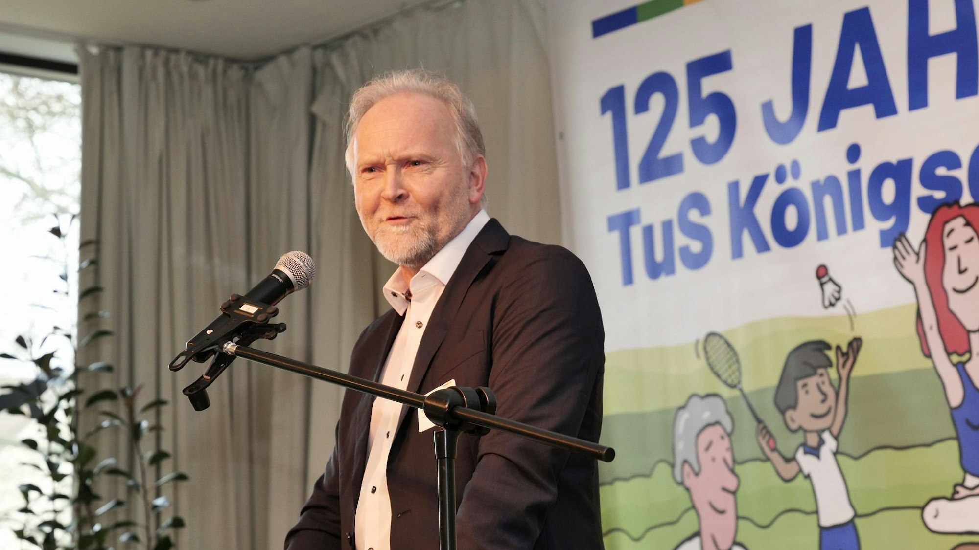 Auf dem Bild ist ein Portrait von Gerd Koslwoski am Rednerpult zu sehen.