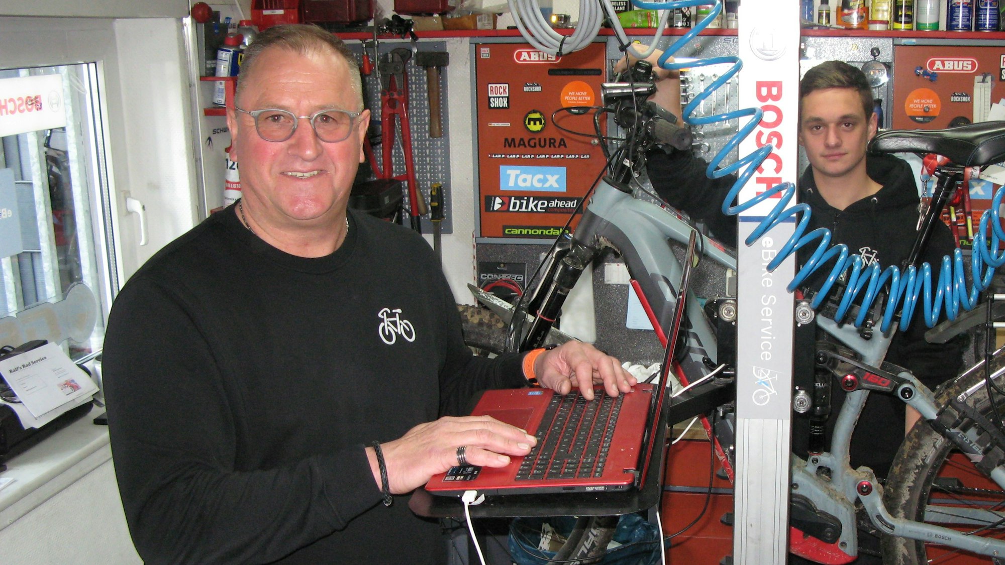 Ralf Wüllenweber (58) kandidiert für das Bürgermeisteramt in der Gemeinde Ruppichteroth. Hier in seinem Fahrradgeschäft mit Mitarbeiter Nils Schneider.