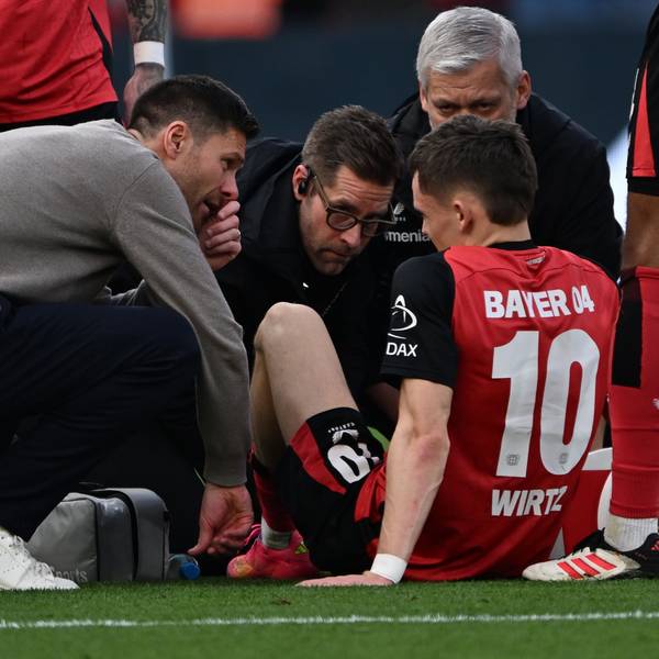 Leverkusens Trainer Xabi Alonso (l) spricht mit Florian Wirtz, der verletzt auf dem Platz sitzt.