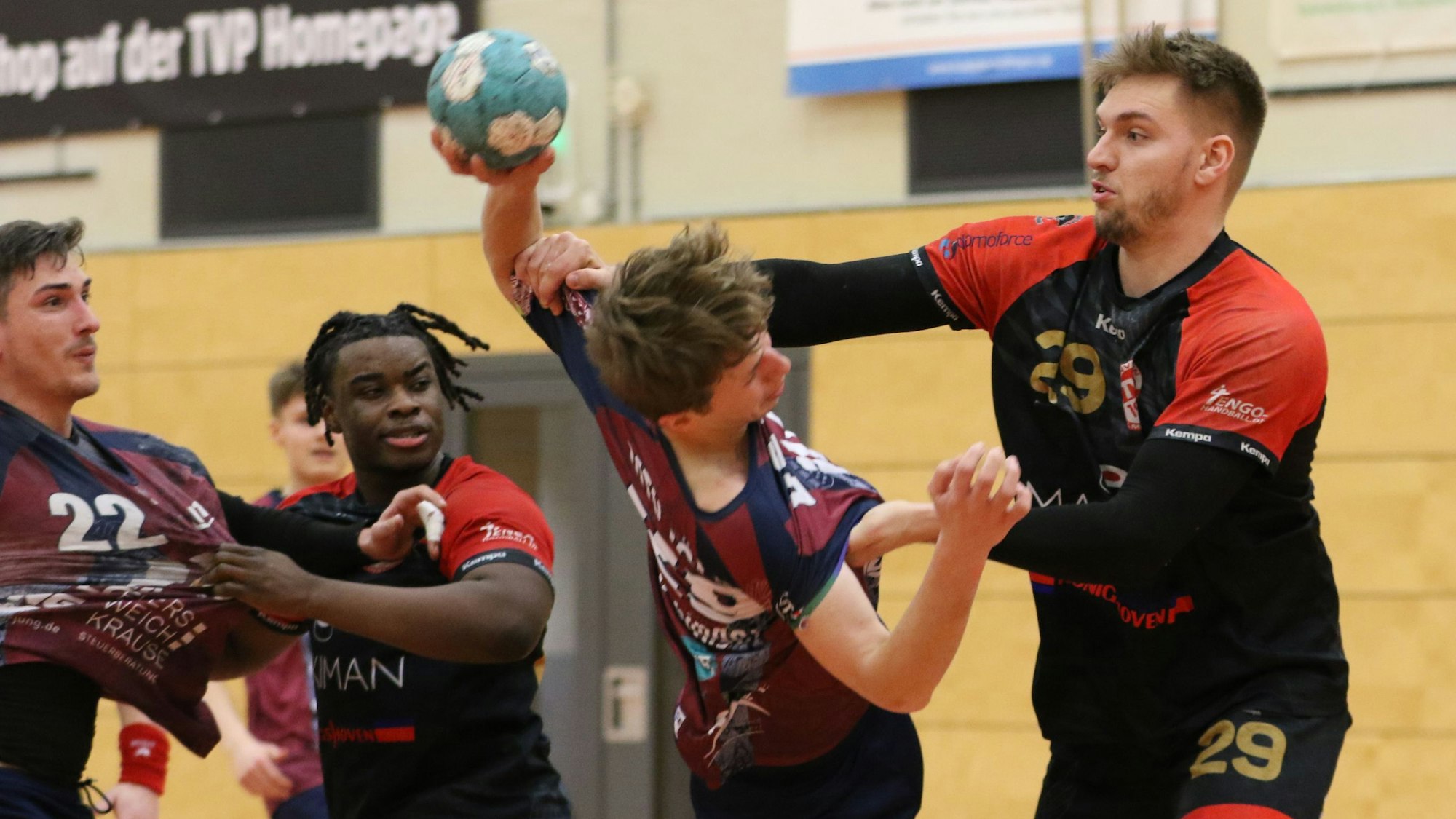 Palmersheims Robin Voiß greift mit beiden Armen den ballführenden Gegner an. Eine Hand geht an den Oberarm, die andere an die Brust. Ein Mitspieler und ein Gegenspieler schauen zu.