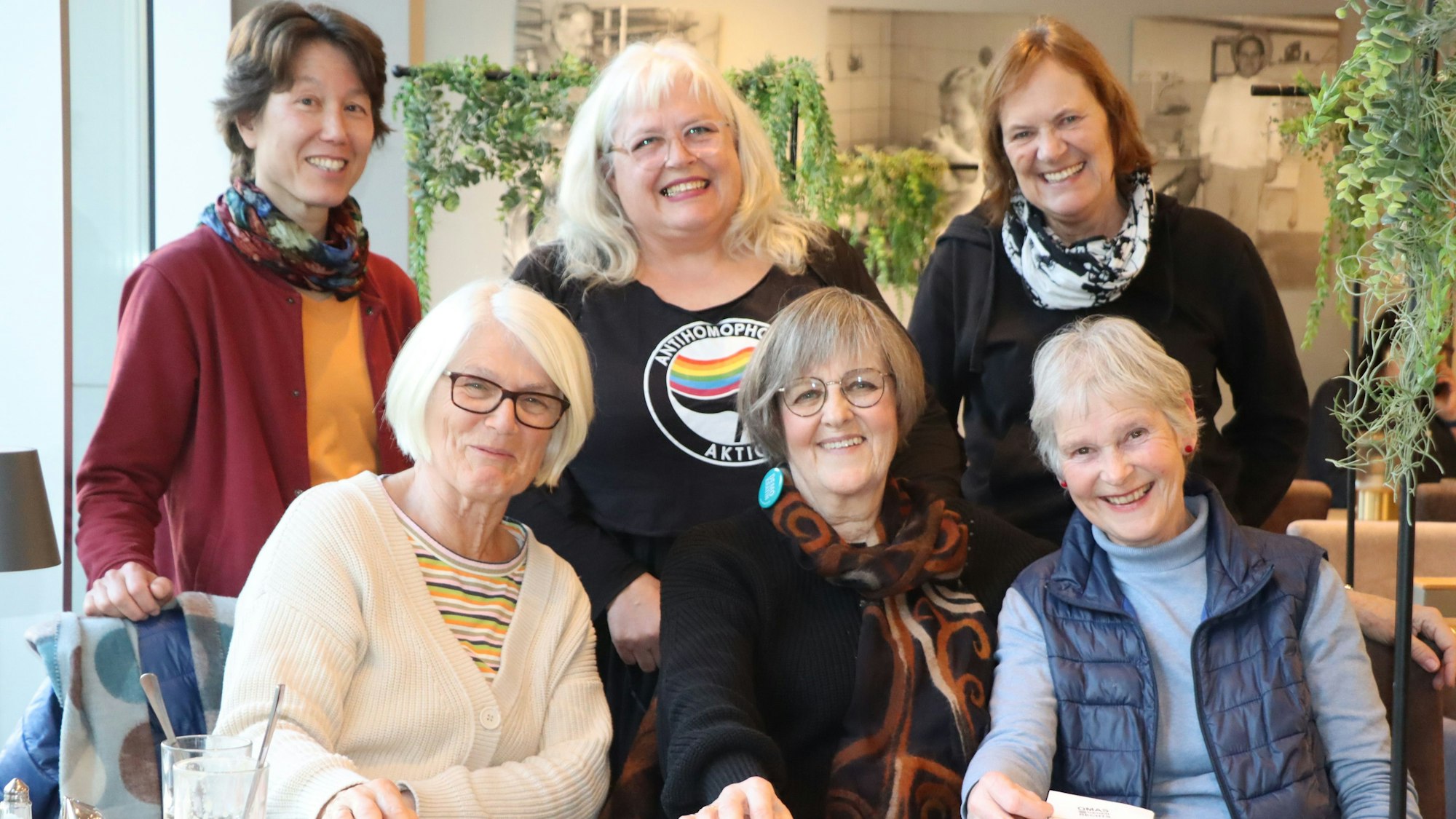 Auf dem Bild sind sechs Mitgliederinnen der Omas gegen Rechts zu sehen. Drei sitzen in einer Reihe, dahinter stehen drei in einer weiteren. Alle lächeln in die Kamera.