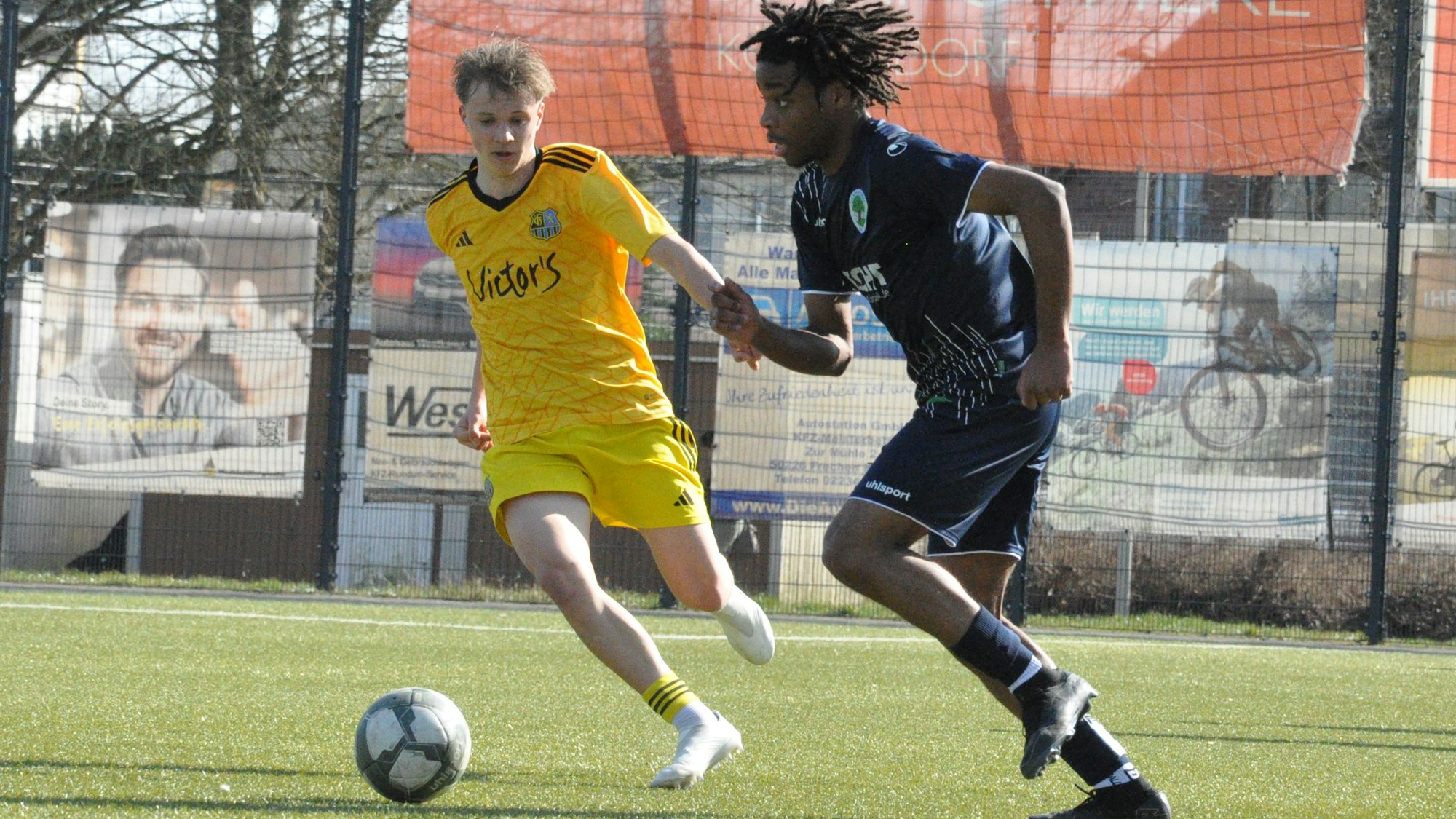 Das Foto zeigt einen Fußballer von BW Königsdorf im dunklen Trikot, der mit einem Saarbrücker Gegenspieler um den Ball kämpft