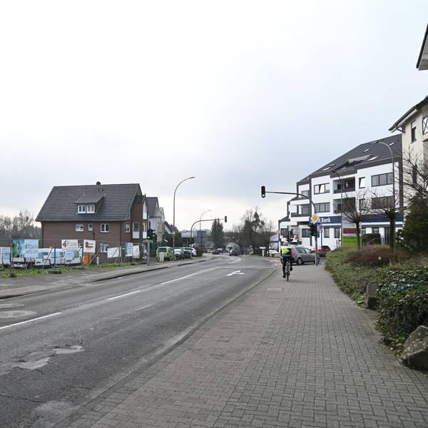Eine Straße, links ein freies Baugelände.