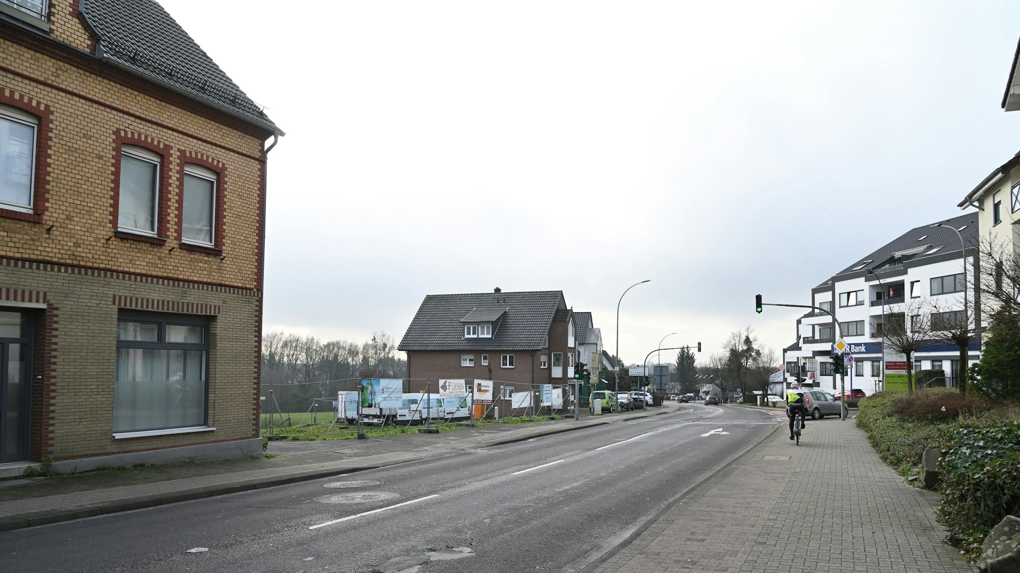 Eine Straße, links ein freies Baugelände.