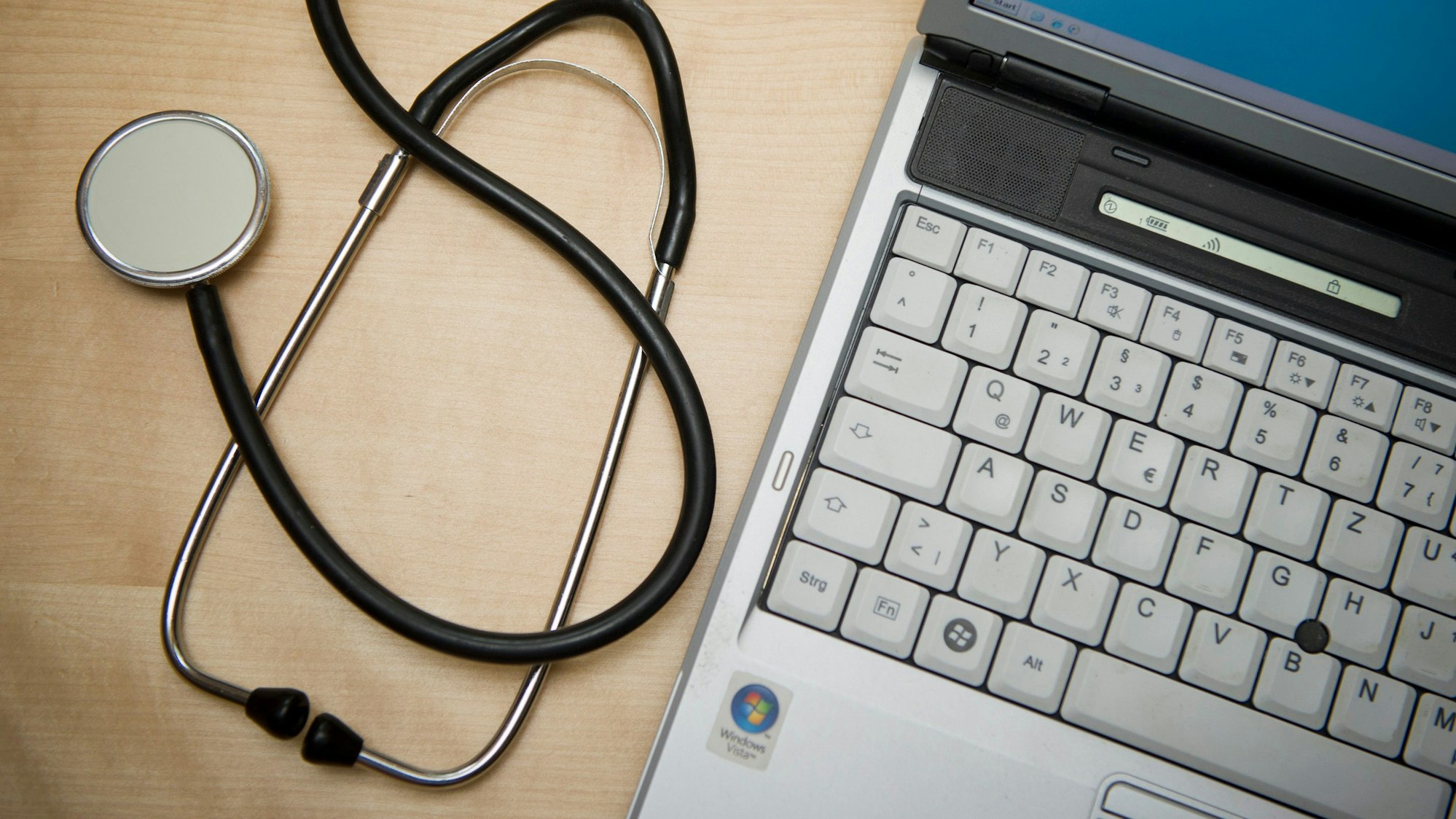 Ein Stethoskop liegt neben einem Laptop.