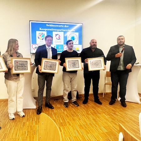 Auf dem Bild stehen Karina Dierks, Regina Hemmersbach-Fontein, Addy Muckes, Mustafa Karakurt, Yavuz Karagöz in einer Reihe und halten Kalligrafien ihres Namens hoch. Daneben steht der Laudator Murat Gök.