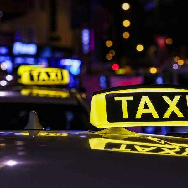 Ein Taxi mit beleuchtetem Taxischild wartet in einer Schlange von Taxen auf Fahrgäste.