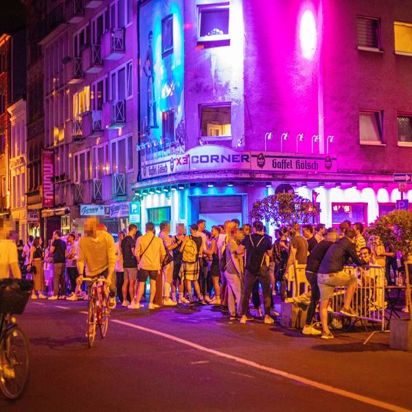 02.06.2021, Köln: Vor dem X3 Corner in der Schaafenstraße stehen zahlreiche Menschen. Nach einem sommerlichen Tag mit warmen Temperaturen sind am späten Abend noch zahlreiche Menschen unterwegs. Einige Einschränkungen zur Eindämmung des Coronavirus wurden in den vergangen Tagen gelockert. Zahlreiche Vorschriften wie Kontaktbeschränkungen gelten aber weiterhin, werden jedoch von vielen ignoriert. Foto: Matthias Heinekamp