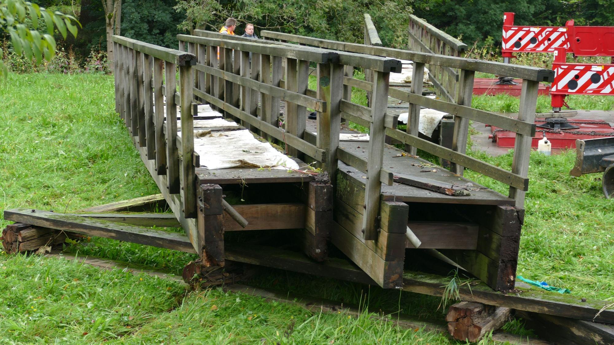 Auf einer Wiese bei Lohmar-Naafshäuschen liegen Teile der demontierten Holzbrücke über die Agger.