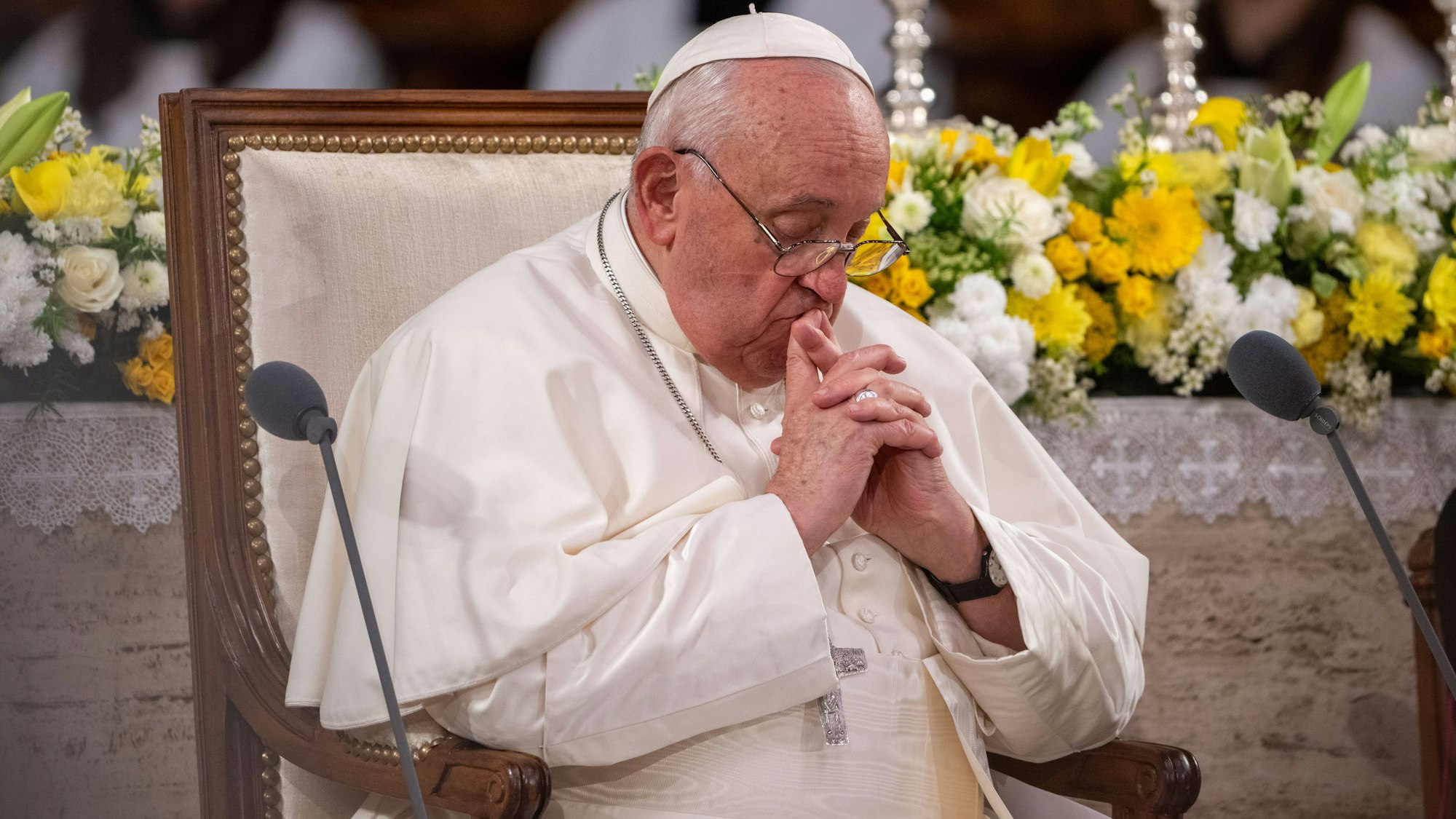 Papst Franziskus sitzt mit gefalteten Händen in der Kathedrale Notre Dame.