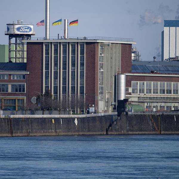 Die Flaggen der USA (l-r), der Ukraine und der Bundesrepublik Deutschland wehen über dem Dach eines Gebäudes der Fordwerke. Arbeitgeber- und Arbeitnehmervertreter sorgen sich um den Industriestandort und zigtausende daran hängende Arbeitsplätze in Nordrhein-Westfalen.