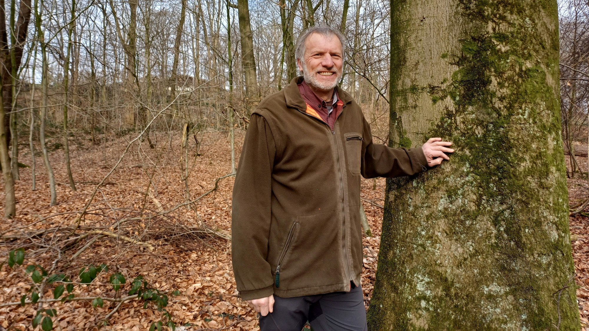 Ein Mann steh an einem Baum.