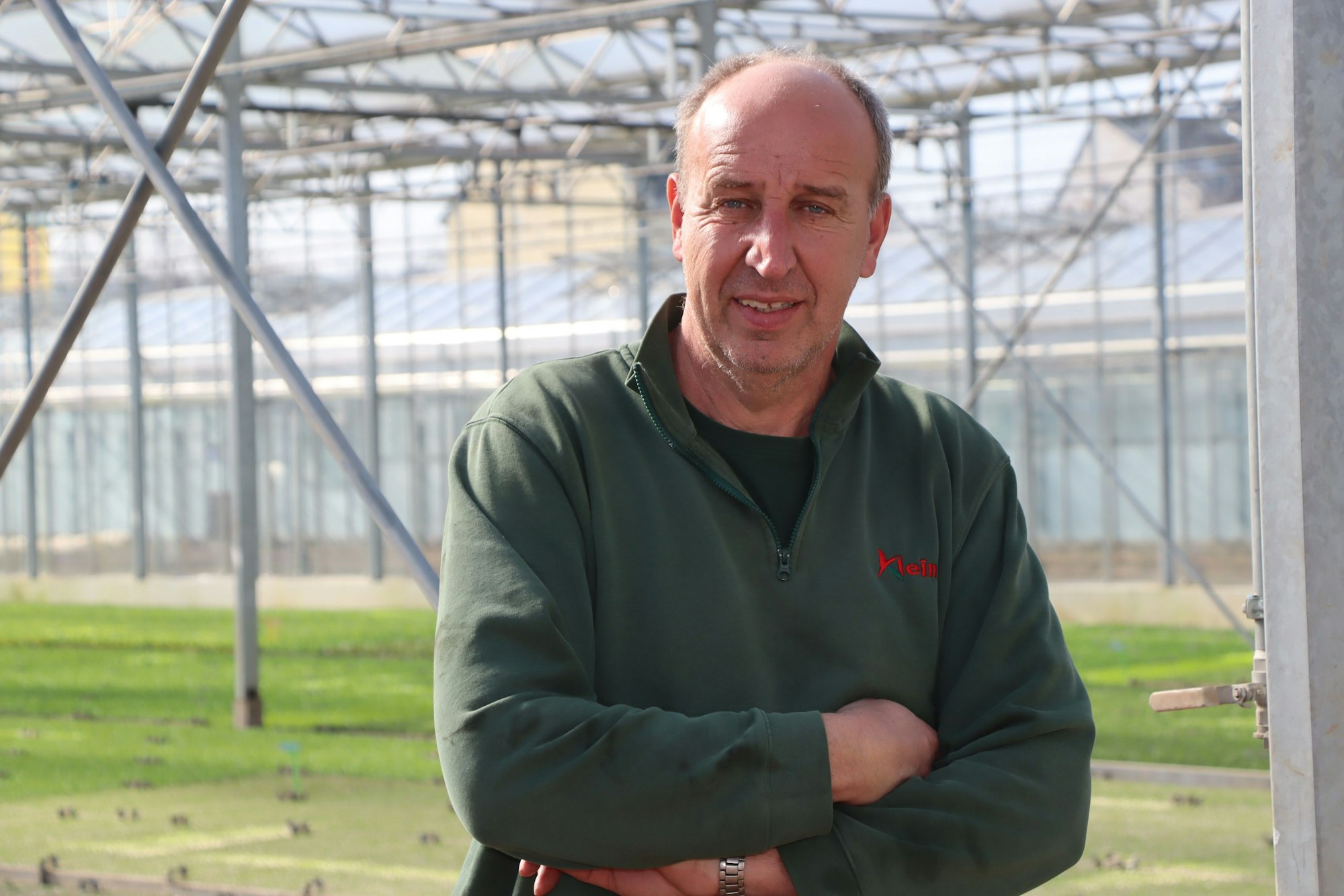 Das Bild zeigt den Landwirt in seinem Gewächshaus. Er trägt einen grünen Pulli.