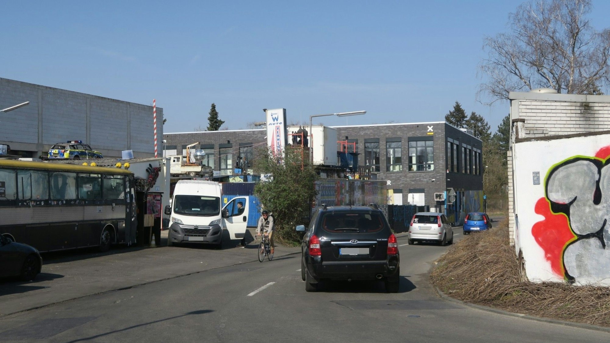 Auf der Vogelsanger Straße im Bereich einer Kurve fahren drei Autos und ein Radfahrer.