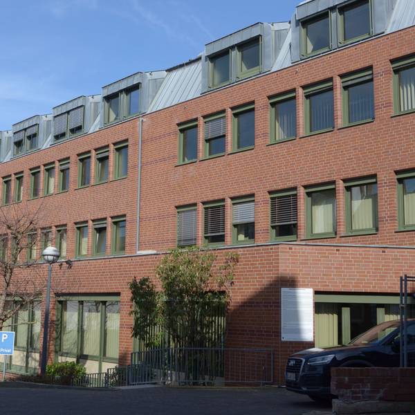Das Bild zeigt ein Bürogebäude, im Hintergrund die Herz-Jesu-Kirche.