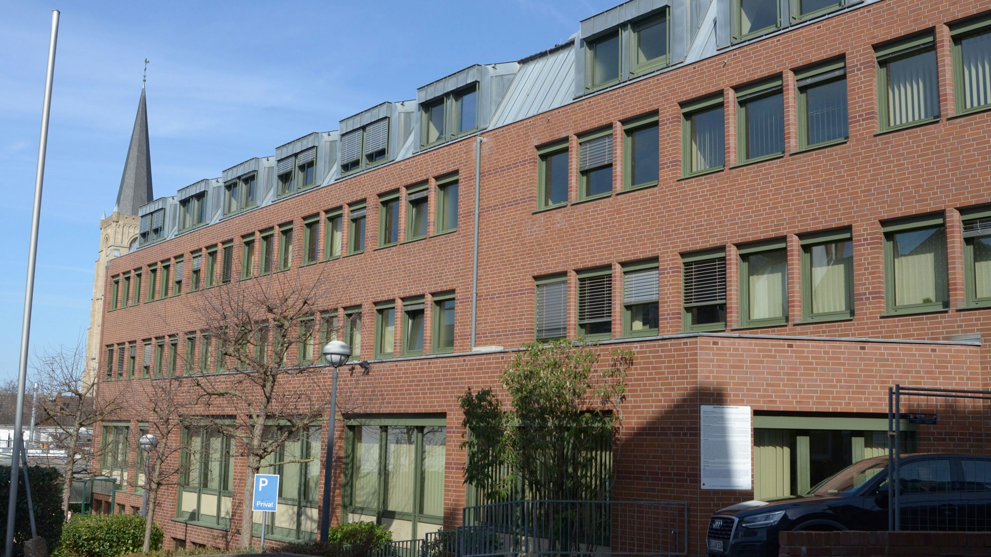 Das Bild zeigt ein Bürogebäude, im Hintergrund die Herz-Jesu-Kirche.