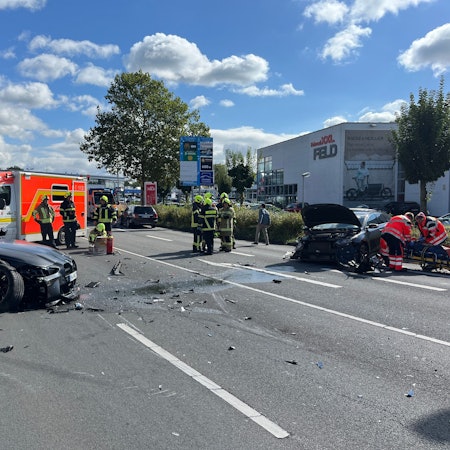 Mehrere beschädigte Autos, ein Rettungswagen und Einsatzkräfte stehen auf ener Fahrbahn