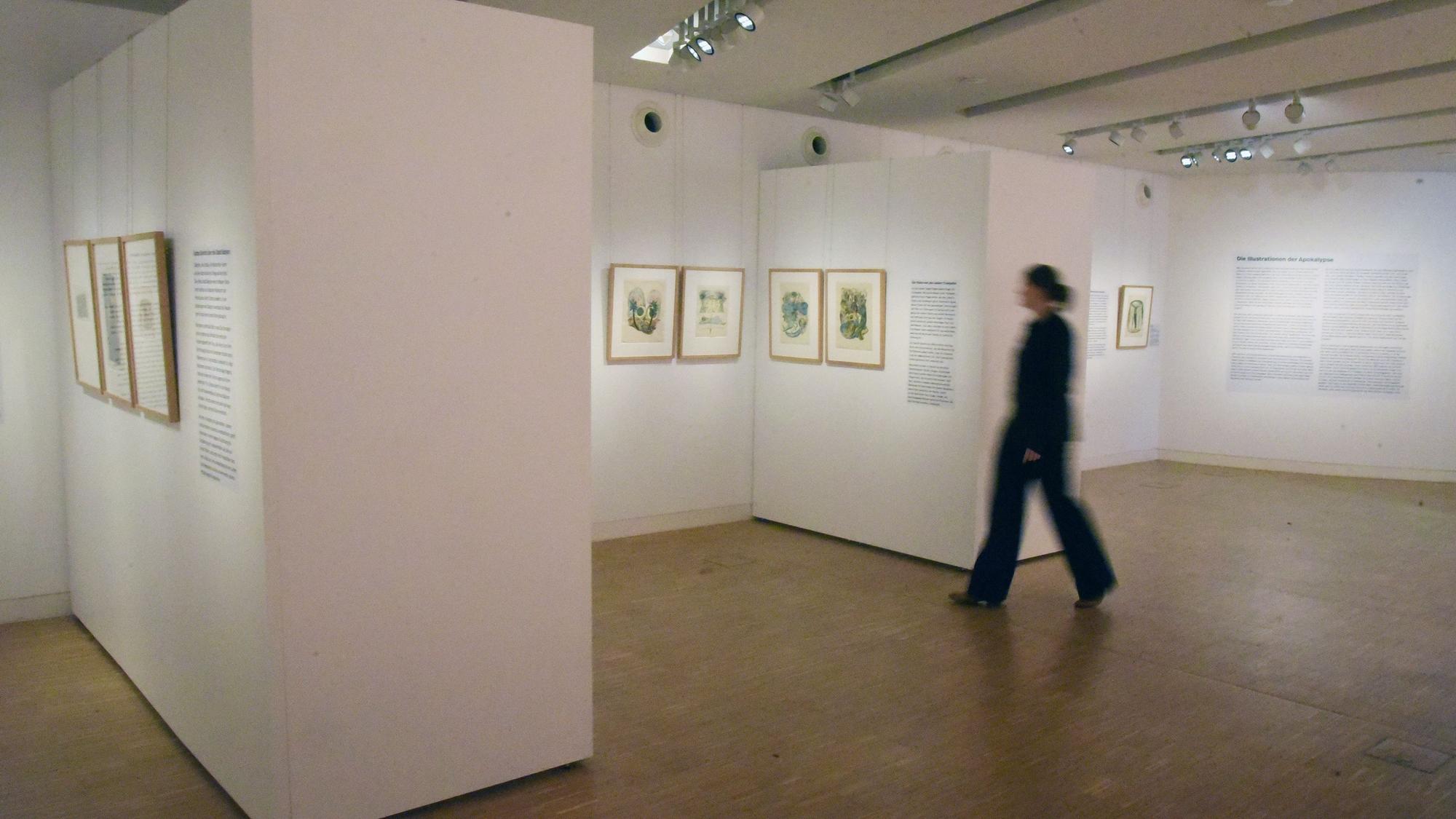 Eine Frau schreitet durch einen Ausstellungsraum.