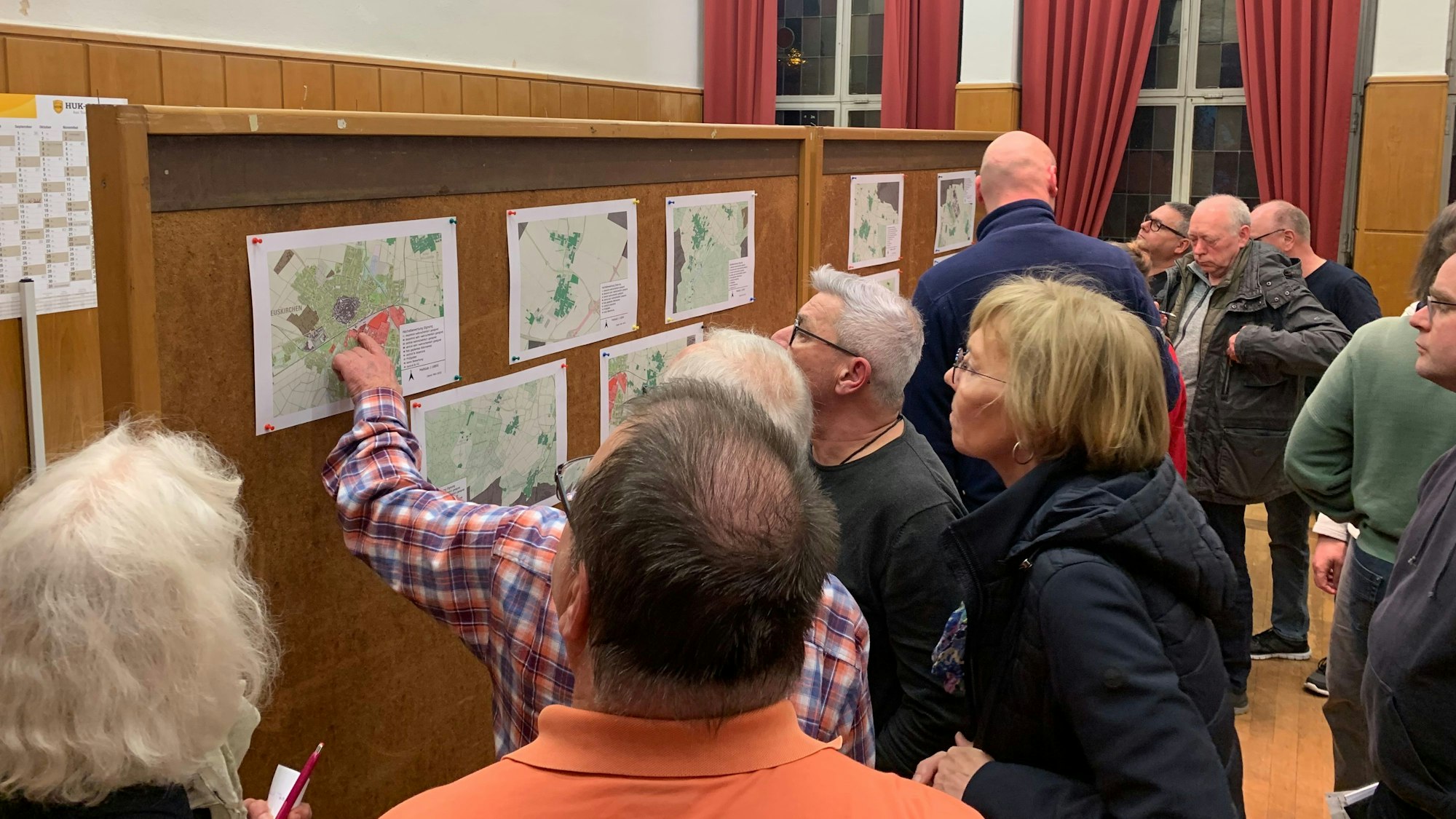 Besucherinnen und Besucher schauen sich Darstellungen an, die an Stellwänden hängen.