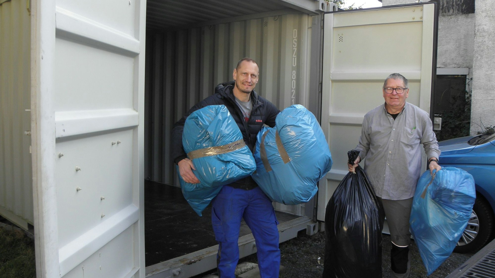 10.03.2025 Spezielles "Zwischenlager": Bernd Thrum (links) und Kurt Schröder tragen Kleidersäcke in einen hochseefesten Seecontainer.