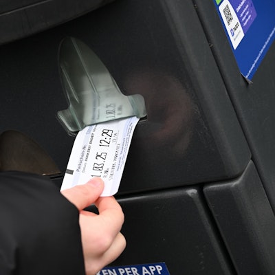 Eine Hand zieht einen Parkschein aus einem Automaten.