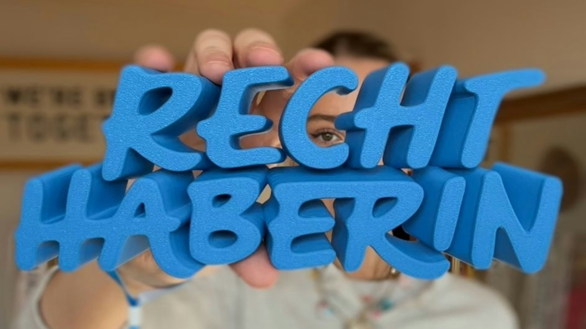 Helena Bleicher hält ein Schild mit der Aufschrift "Rechthaberin" in die Kamera.