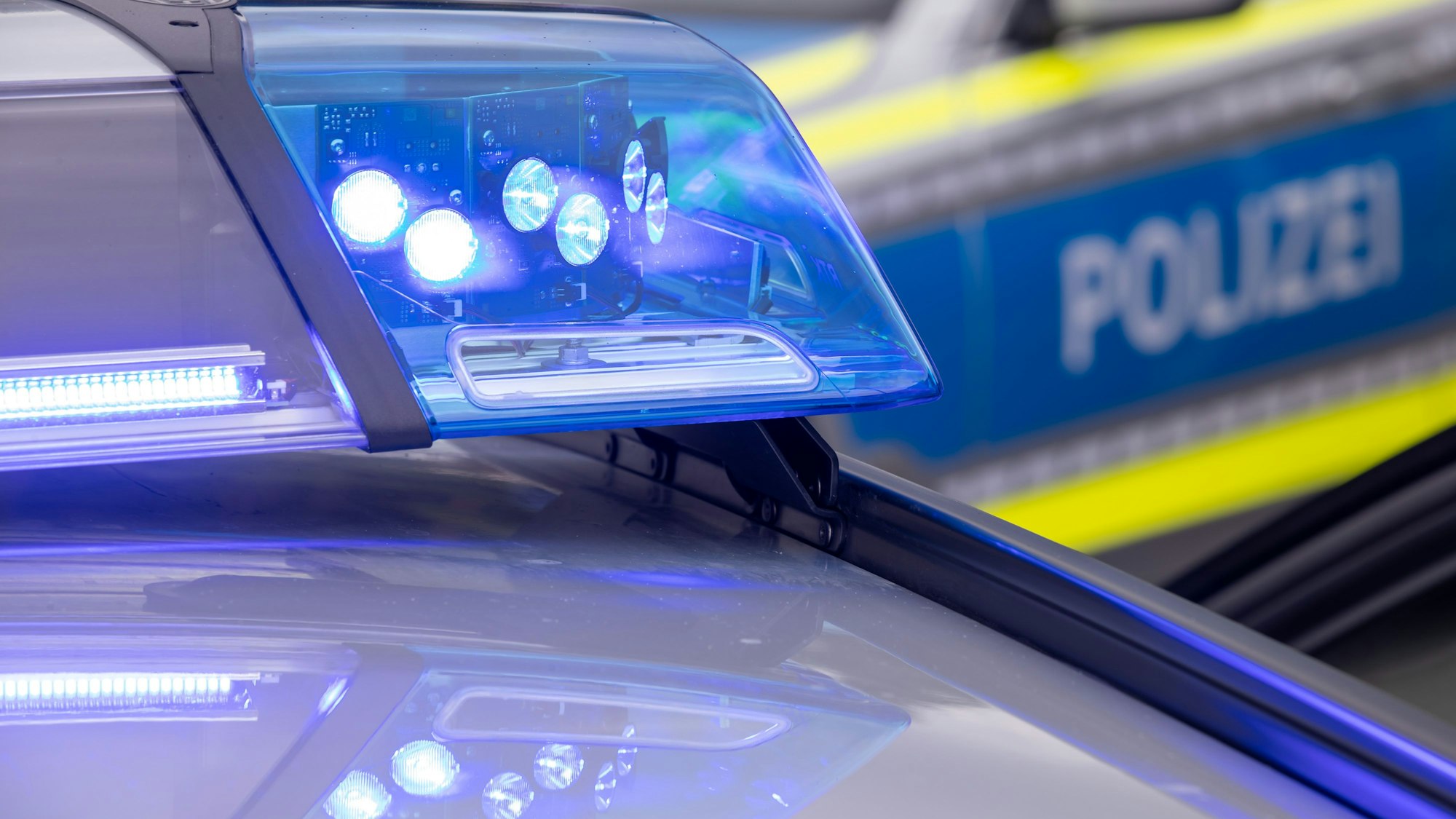 Ein Blaulicht auf dem Dach eines Polizeifahrzeugs leuchtet in der Dunkelheit.