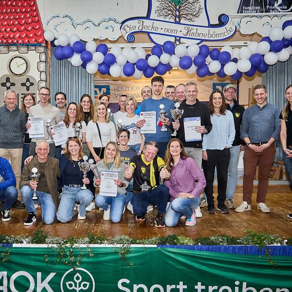 Zahlreiche Frauen und Männer stehen und hocken auf der Bühne im Dorfsaal in Scheven. Sie halten Pokale und Urkunden in den Händen, die sie beim Eifelcup gewonnen haben.