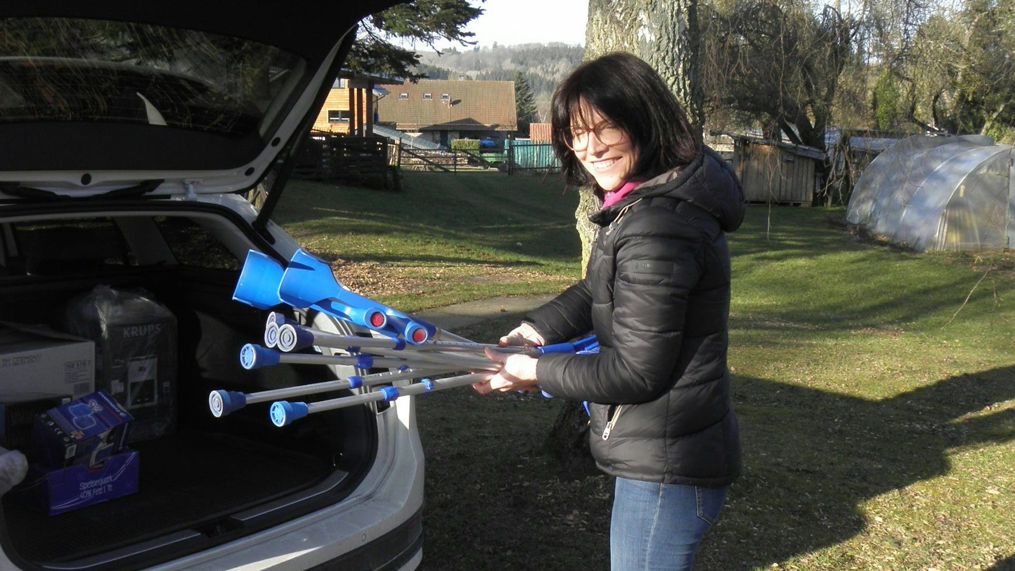 Monika Kropp holt Gehhilfen aus dem Kofferraum eines Autos.