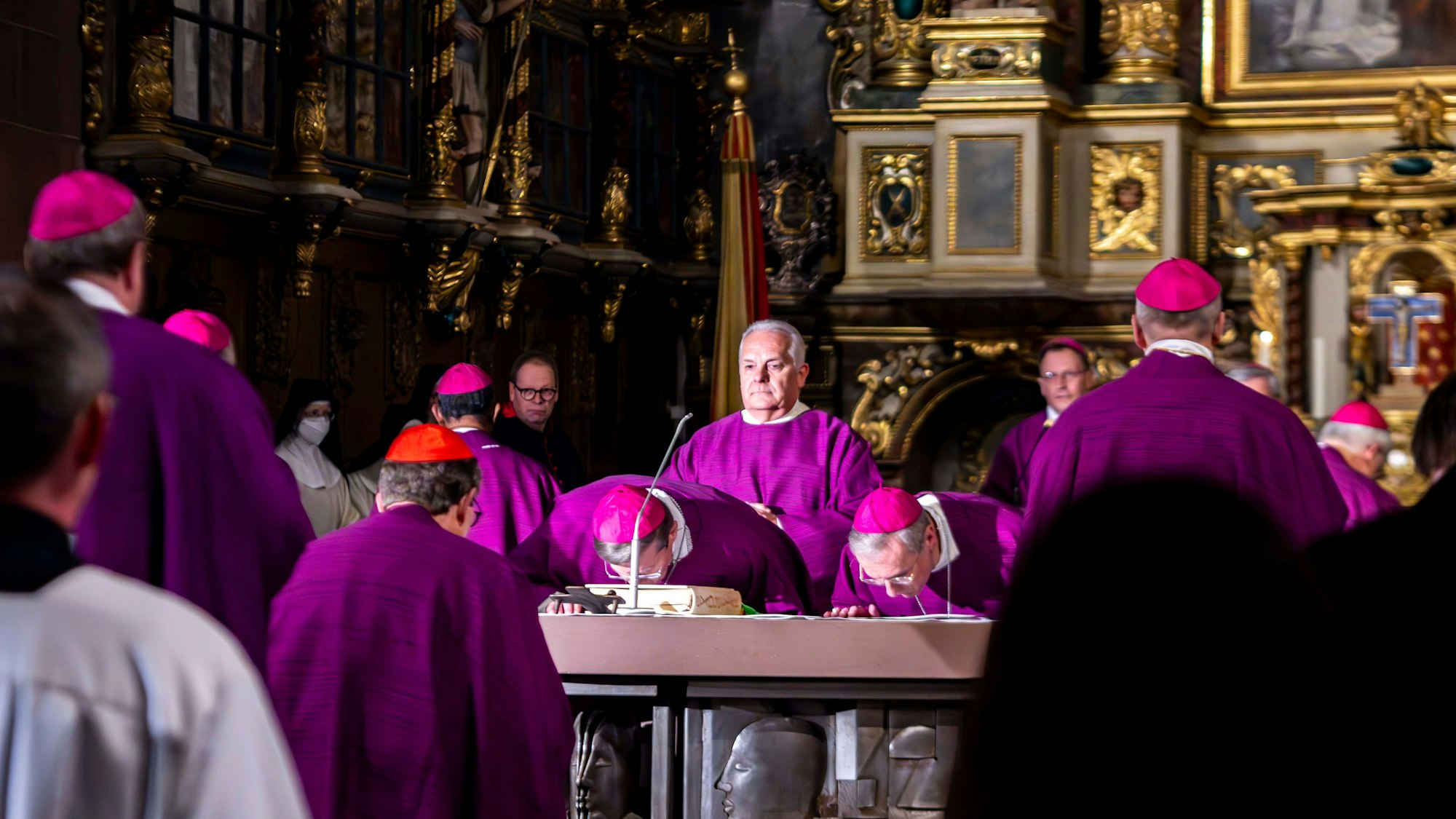 Viele Bischöfe in lila Gewändern stehen um einen Altar.