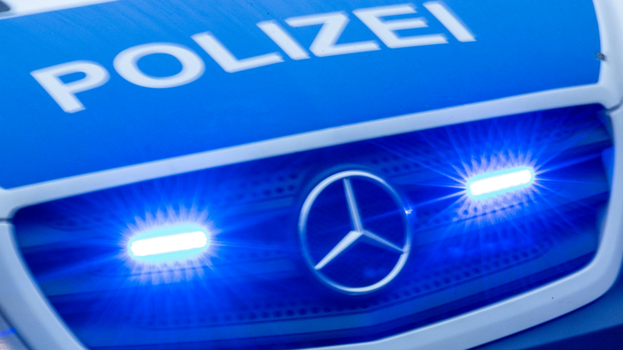 Ein Einsatzfahrzeug der Polizei fährt mit Blaulicht durch eine Stadt.