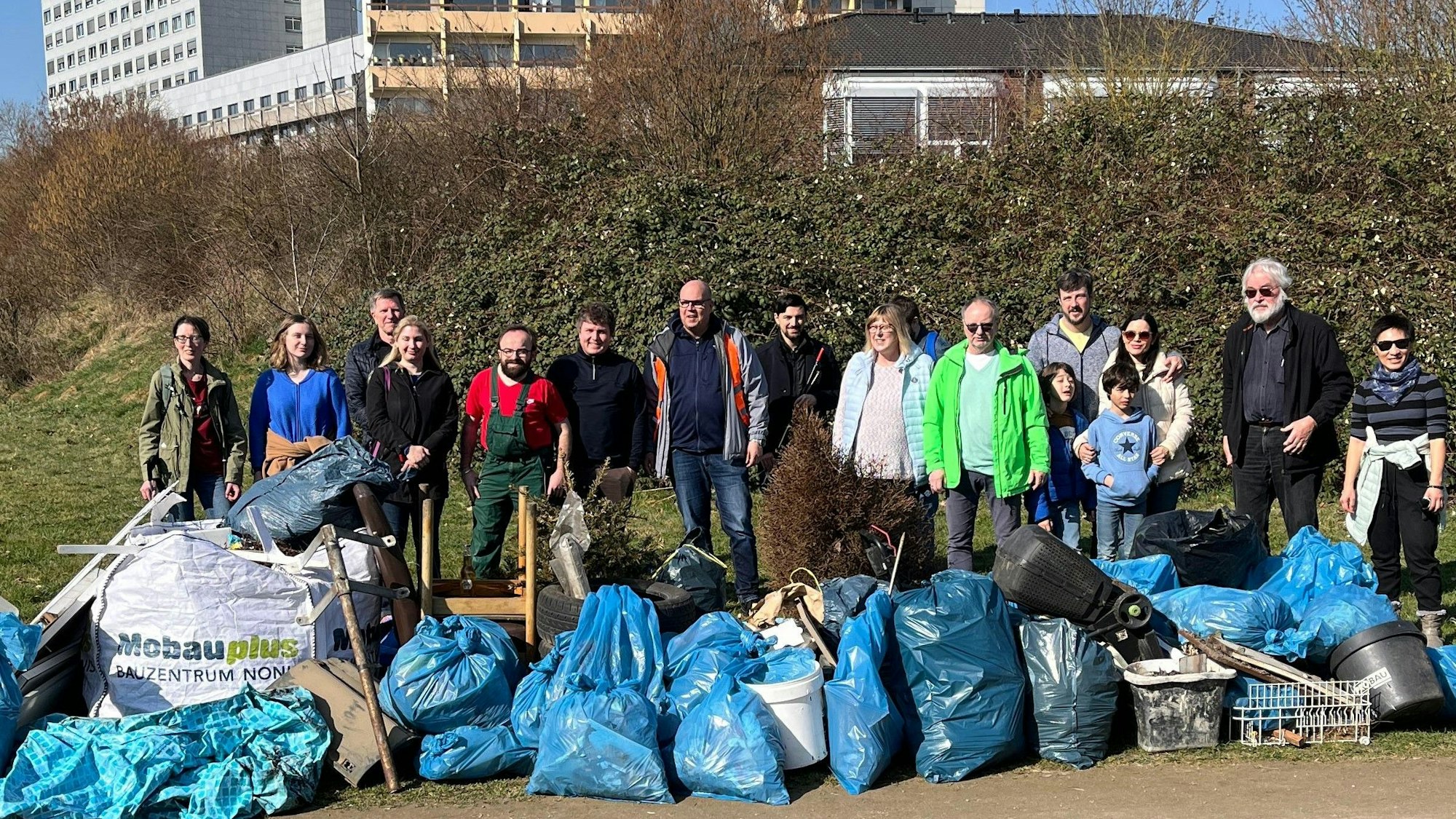 Auf dem Bild sind ehrenamtliche Müllsammler zu sehen, die eine große Menge an blauen Abfallsäcken gefüllt und Sperrmüll aufgeräumt haben.