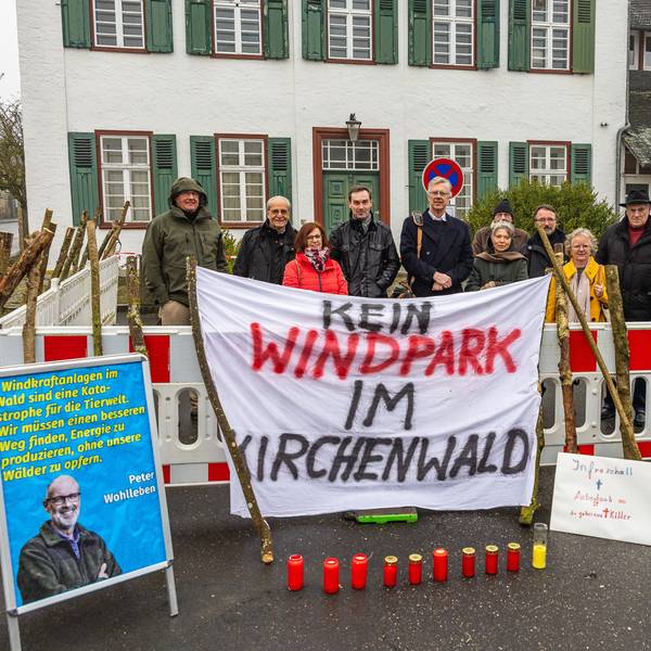Eine Gruppe steht hinter einem Transparent, auf dem steht: „Kein Windpark im Kirchenwald“.