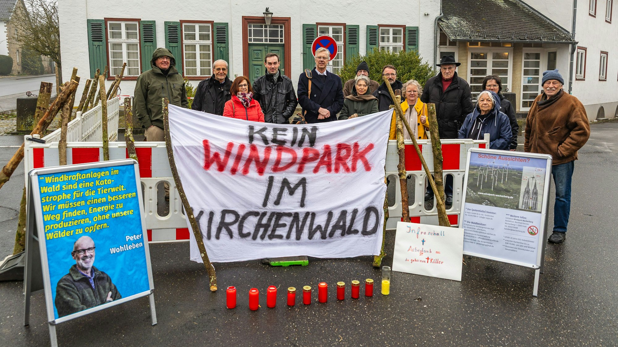 Eine Gruppe steht hinter einem Transparent, auf dem steht: „Kein Windpark im Kirchenwald“.