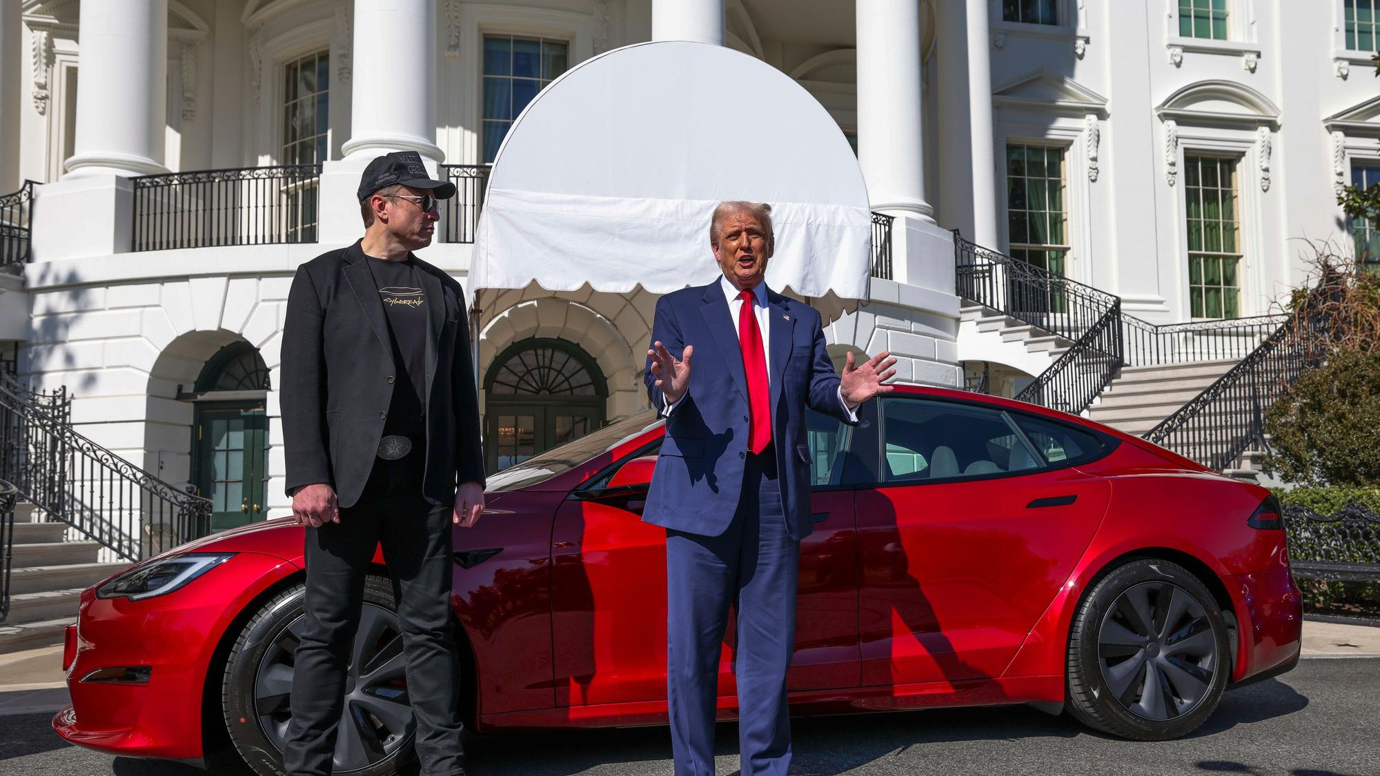 Ds Bild zeigt US-Präsident Donald Trump (r) und Tesla-CEO Elon Muskwie sie zu Reportern vor einem roten Tesla Model S auf dem Südrasen des Weißen Hauses sprechen. Foto: -/Pool/AP/dpa +++ dpa-Bildfunk +++