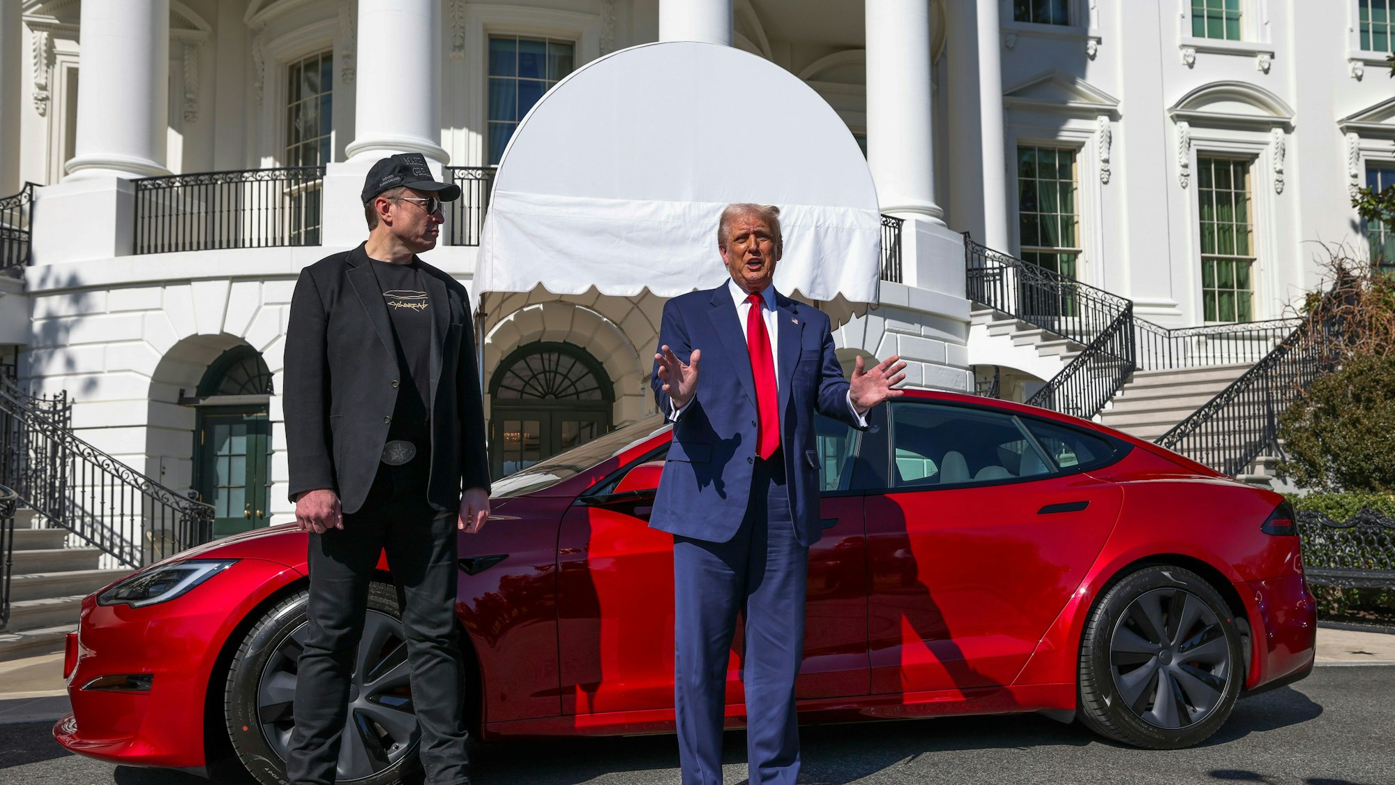 Ds Bild zeigt US-Präsident Donald Trump (r) und Tesla-CEO Elon Muskwie sie zu Reportern vor einem roten Tesla Model S auf dem Südrasen des Weißen Hauses sprechen. Foto: -/Pool/AP/dpa +++ dpa-Bildfunk +++