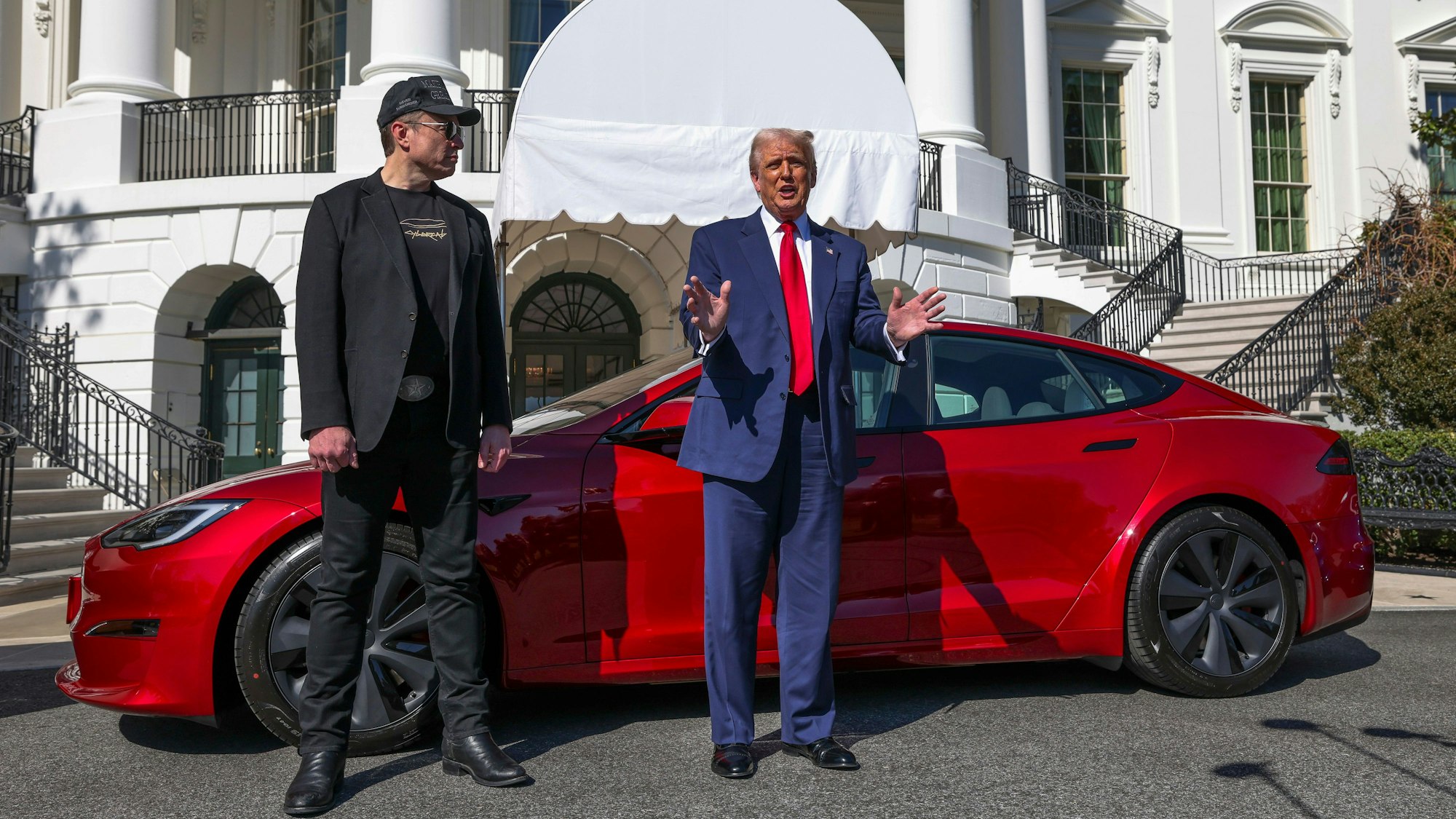 US-Präsident Donald Trump (r) und Tesla-CEO Elon Musk sprechen zu Reportern vor einem roten Tesla Model S auf dem Südrasen des Weißen Hauses.