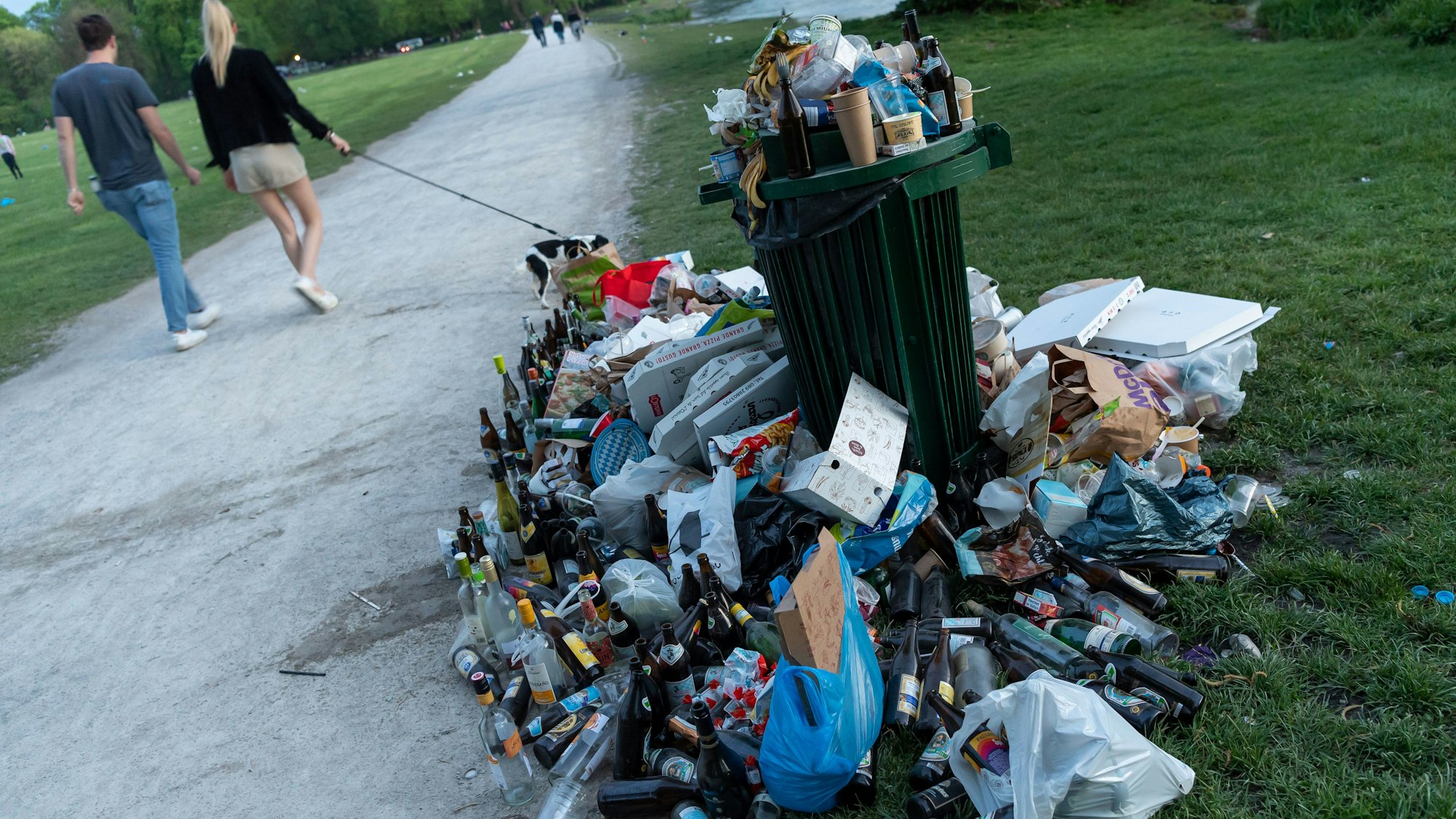 Ein zugemüllter Abfallbehälter in einem Park.