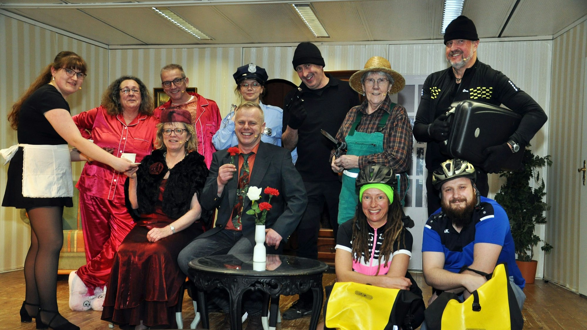 Die Mitglieder des Ensembles haben sich zu einem Gruppenbild formiert und lachen in die Kamera.