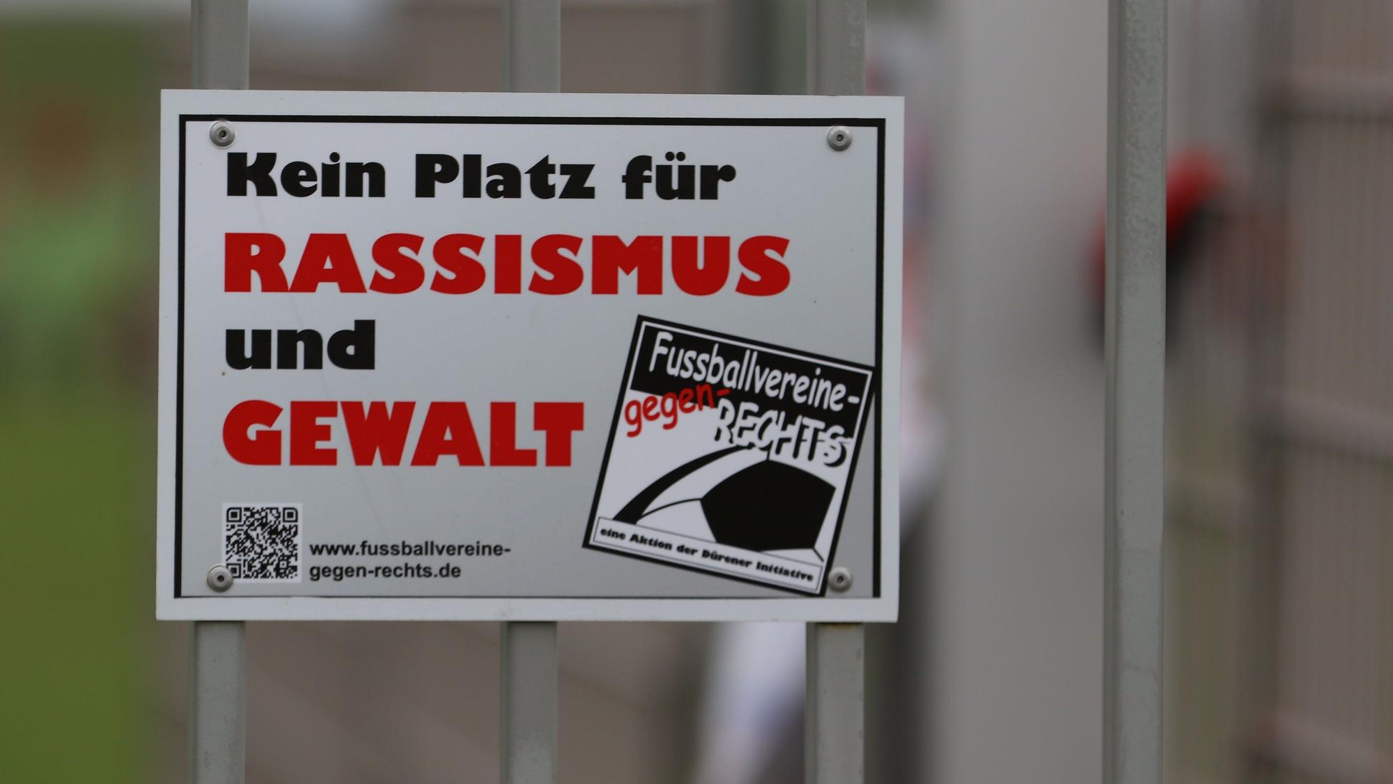 Das Symbolbild zeigt eine Plakette mit der Aufschrift „Kein Platz für Rassismus und Gewalt“.