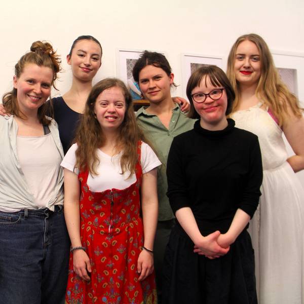 Sechs junge Frauen stehen vor einer Wand mit Bildern