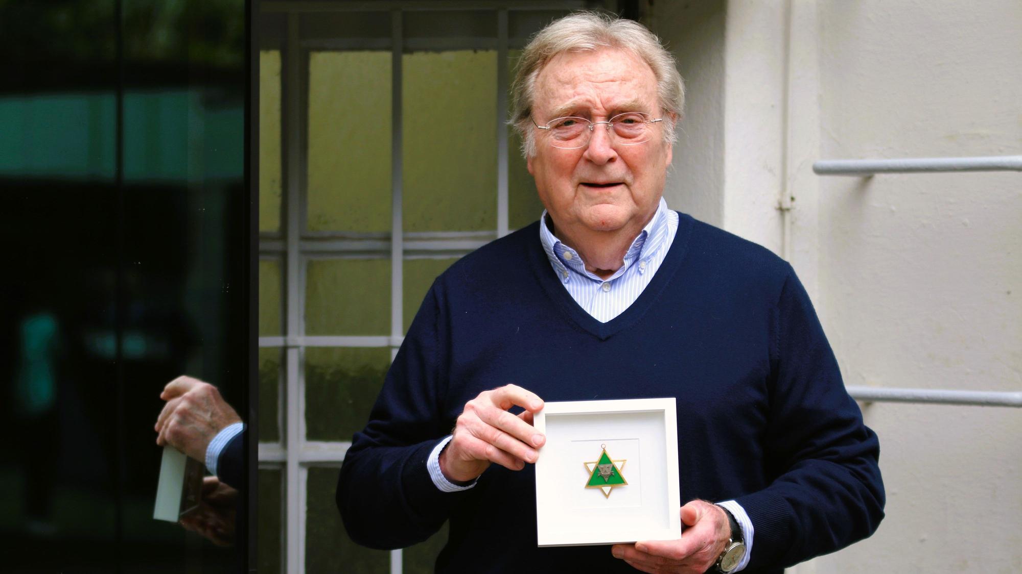 Gerhard Küpper präsentiert den eingerahmten grün-weißen, sternförmigen Karnevalsorden seines Vaters Karl Küpper.