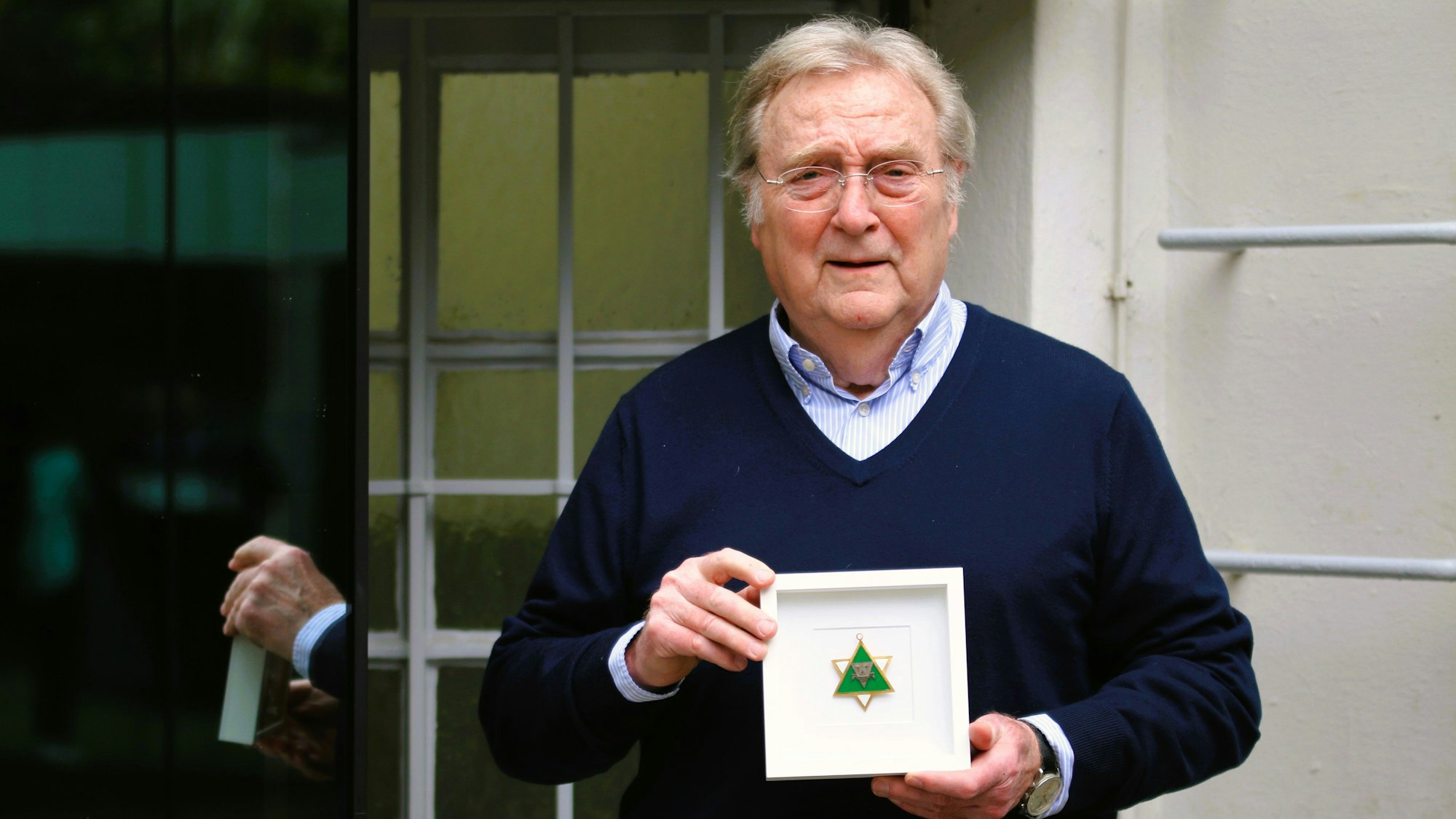 Gerhard Küpper präsentiert den eingerahmten grün-weißen, sternförmigen Karnevalsorden seines Vaters Karl Küpper.