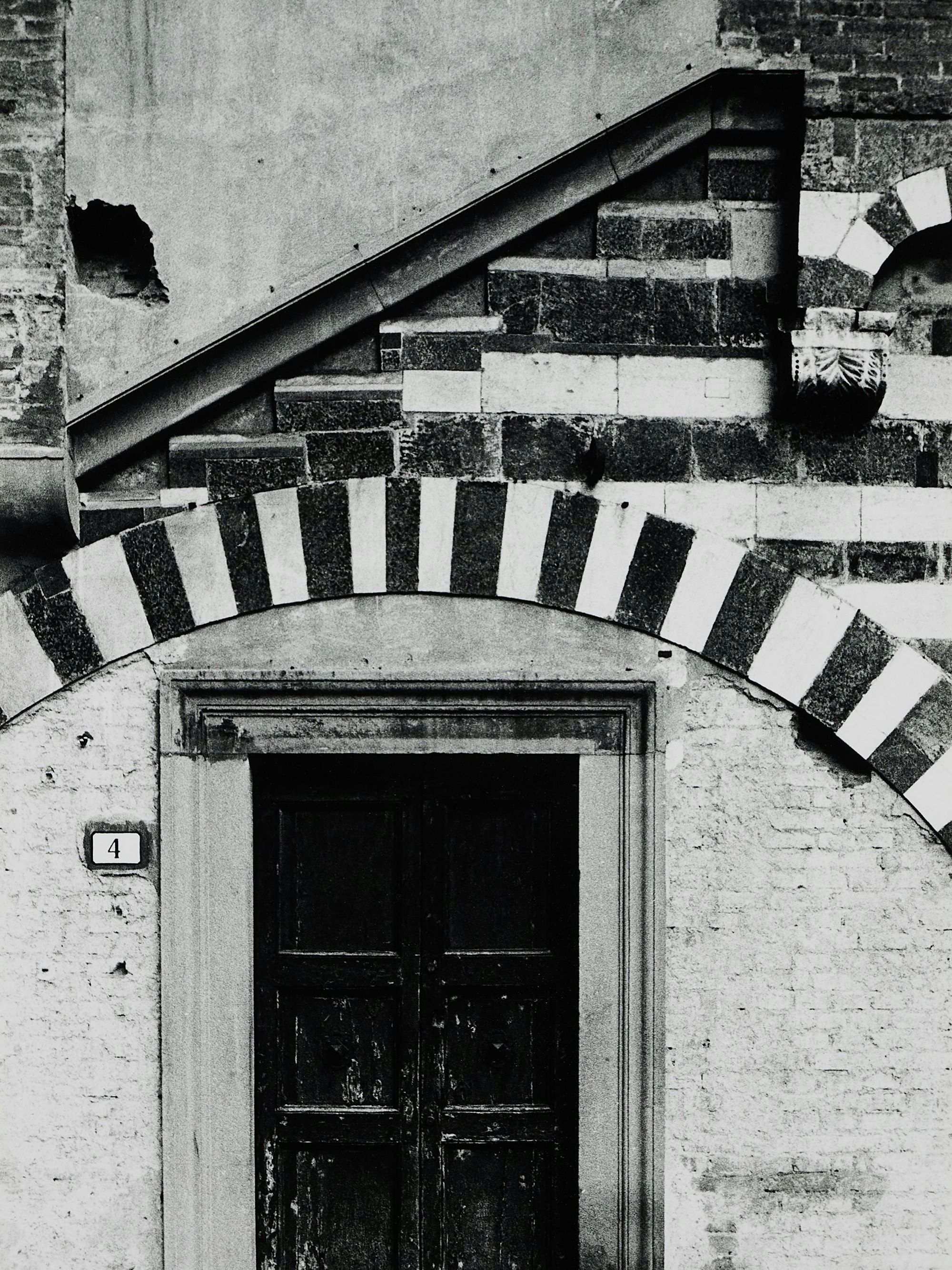Ein Fensterbogen in Schwarz und Weiß an einer Kirche.