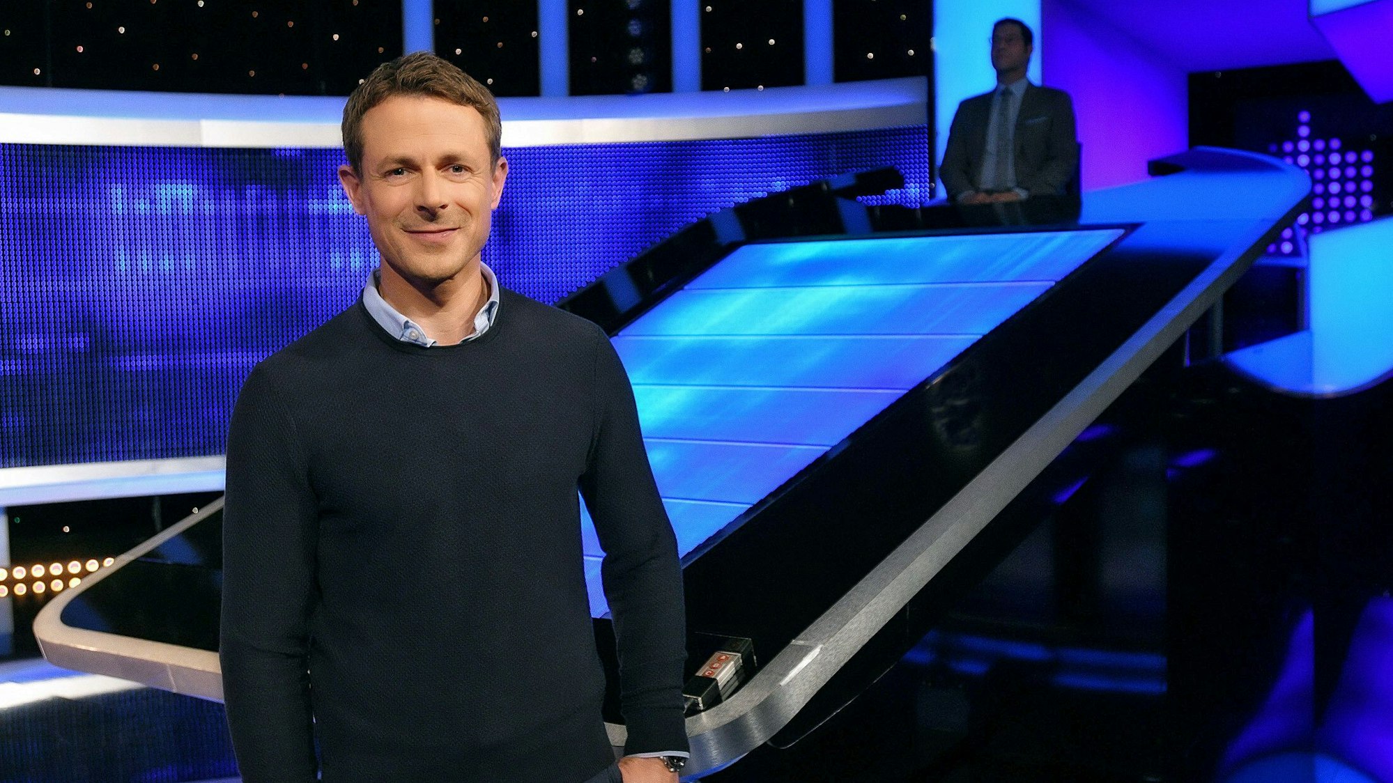 Moderator Alexander Bommes steht in der Studiokulisse von „Gefragt - Gejagt“.