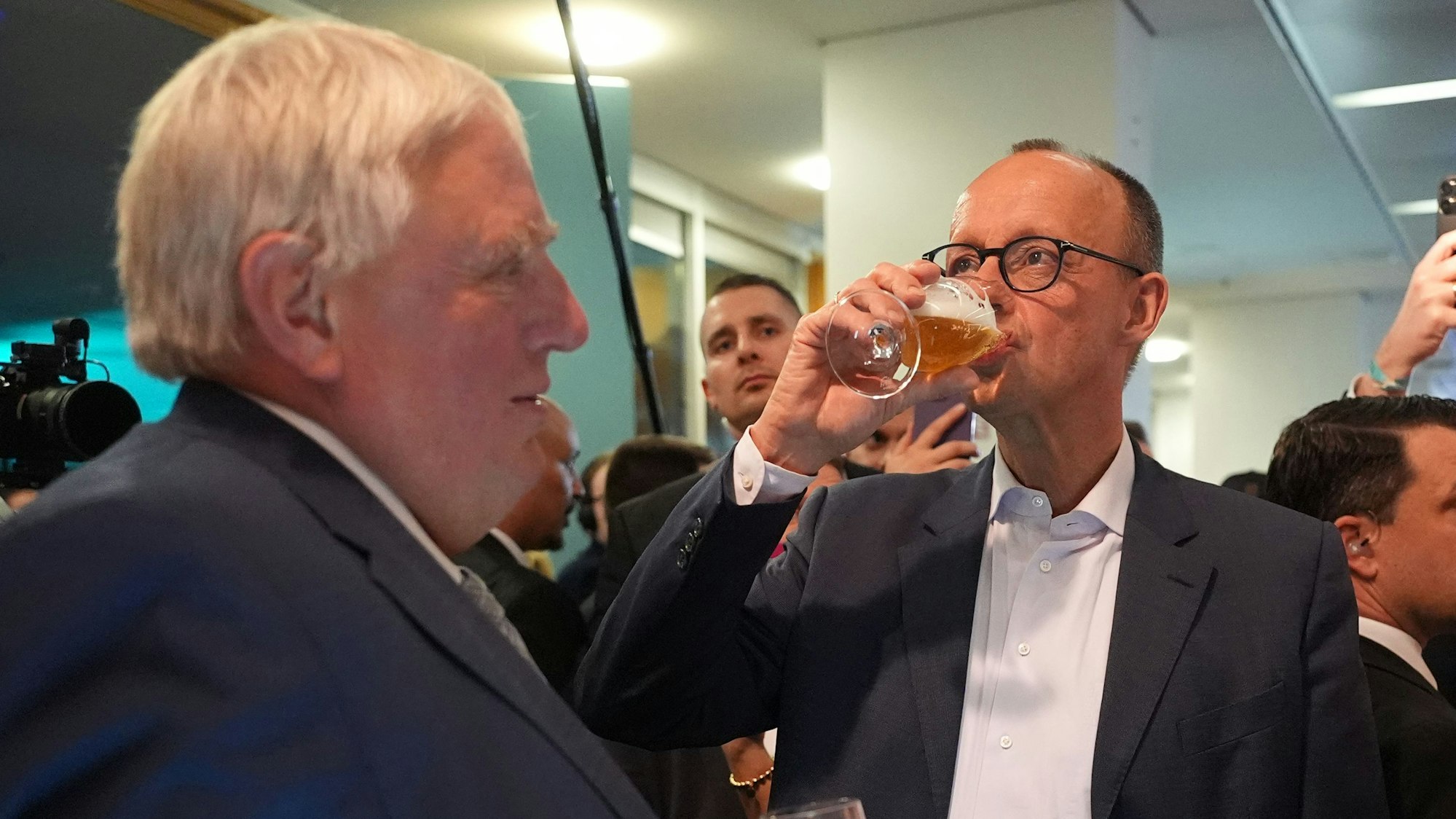 23.02.2025, Berlin: Friedrich Merz (CDU), Parteivorsitzender und Kanzlerkandidat, trinkt neben Karl-Josef Laumann (CDU), Minister für Arbeit, Gesundheit und Soziales des Landes Nordrhein-Westfalen, im Konrad-Adenauer-Haus ein Bier. Am Sonntag fand die vorgezogene Wahl zum 21. Deutschen Bundestag statt. Foto: Marcus Brandt/dpa +++ dpa-Bildfunk +++