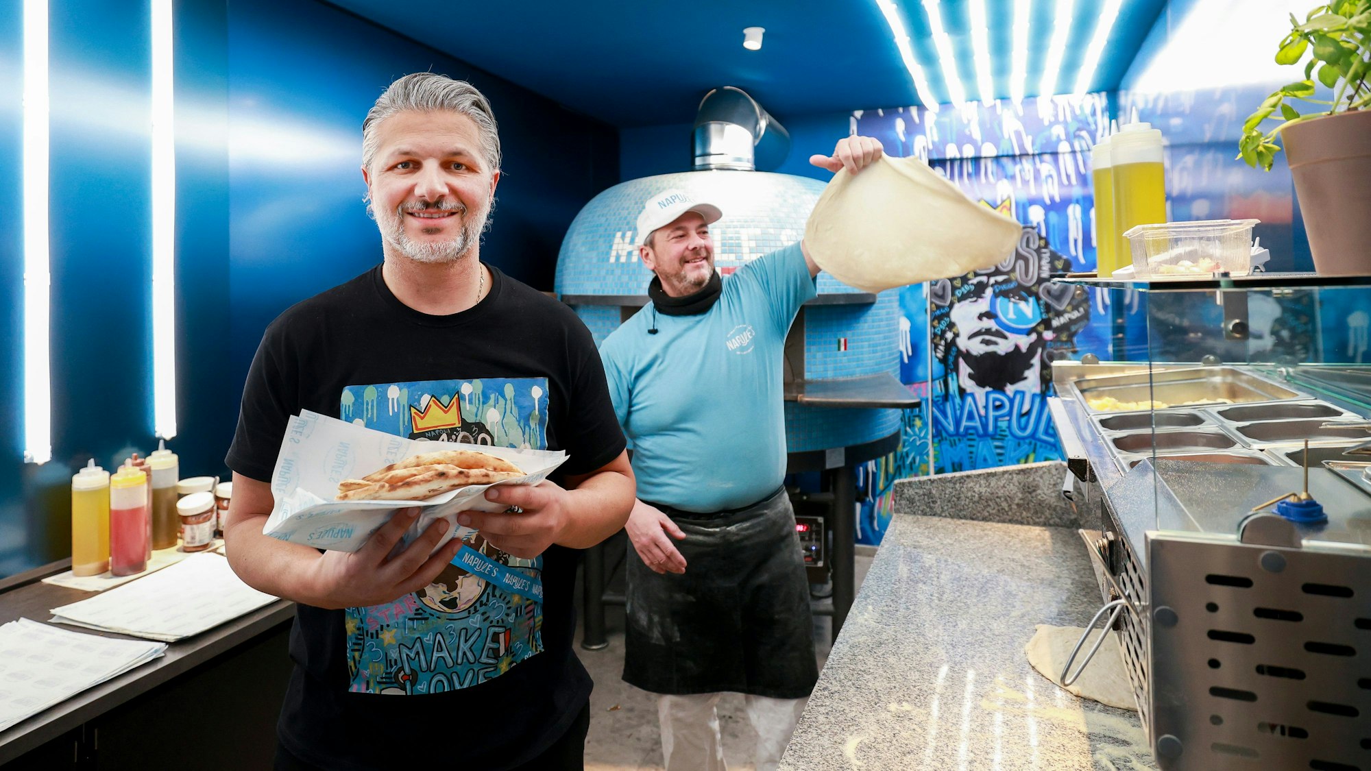 Eröffnung des Napule´s gefaltete Pizza to go.
Im Vordergrund der Inhaber Alfredo Cannizzaro.