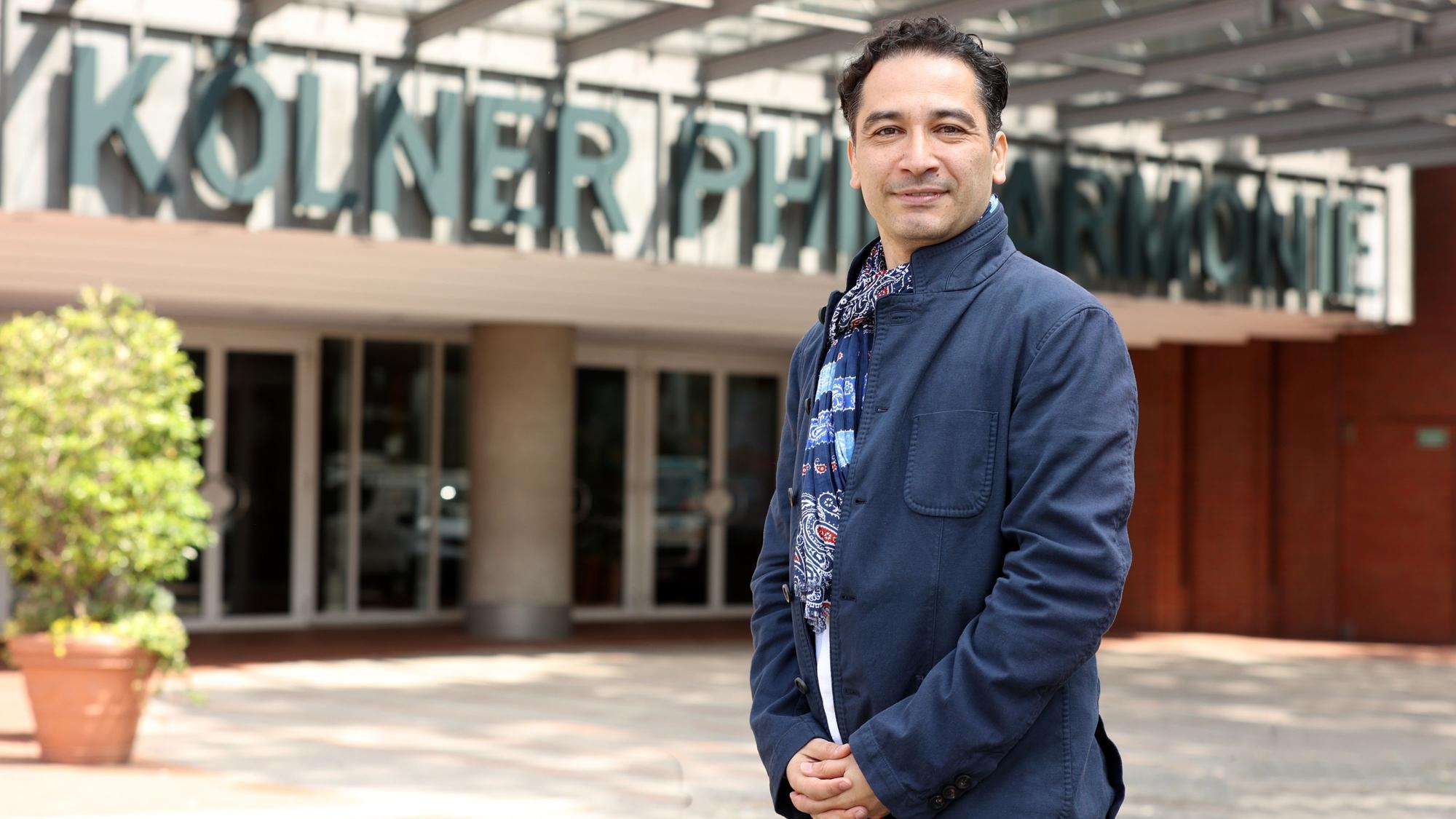Andrés Orozco-Estrada steht vor dem Eingang zur Philharmonie.